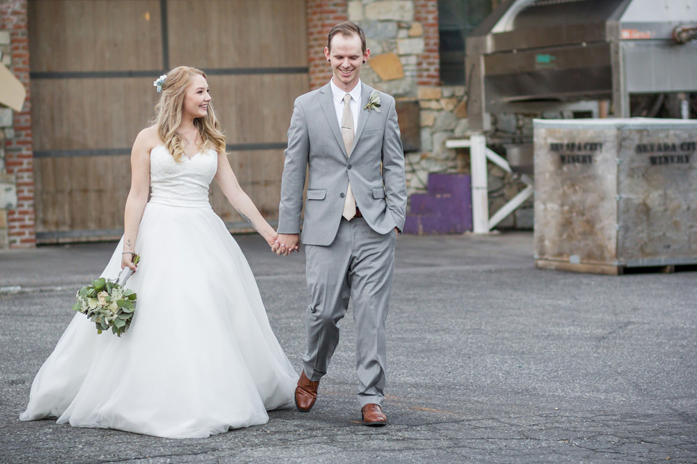 Bride and Groom walking and holding hands on their wedding day by Adrienne & Dani Photography