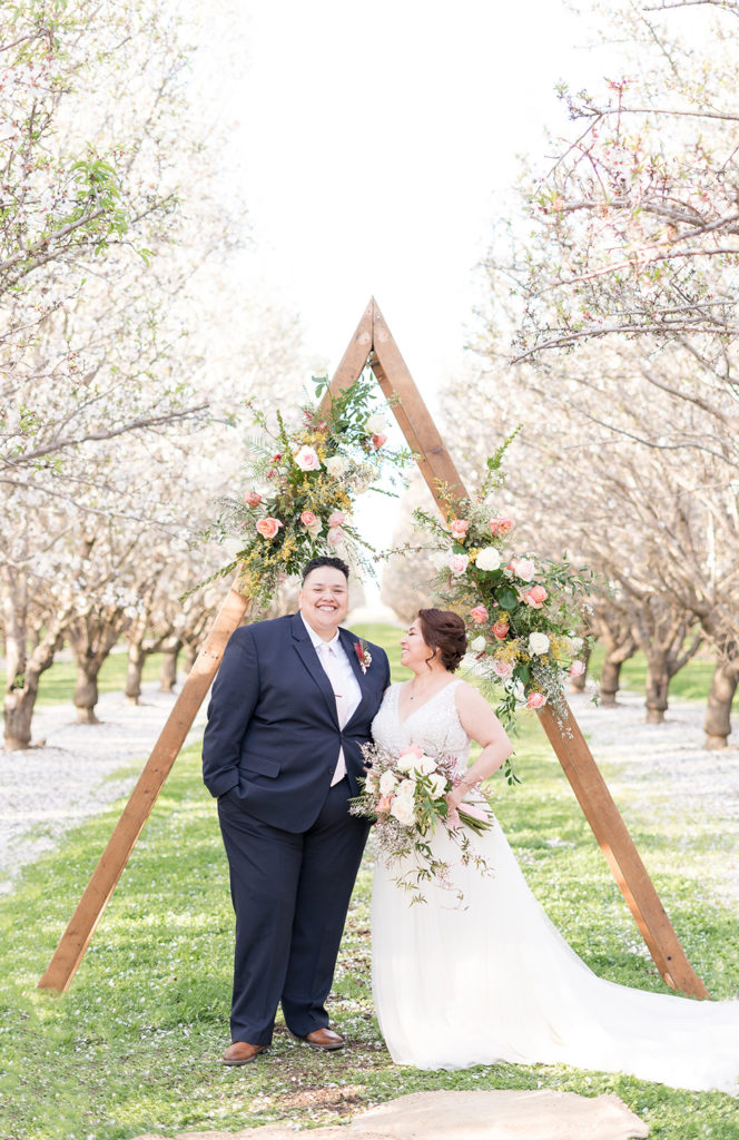 a couple poses under their wedding ceremony arch for their wedding portraits