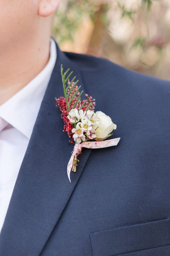 an almond blossom inspired boutonniere against a navy blue suit