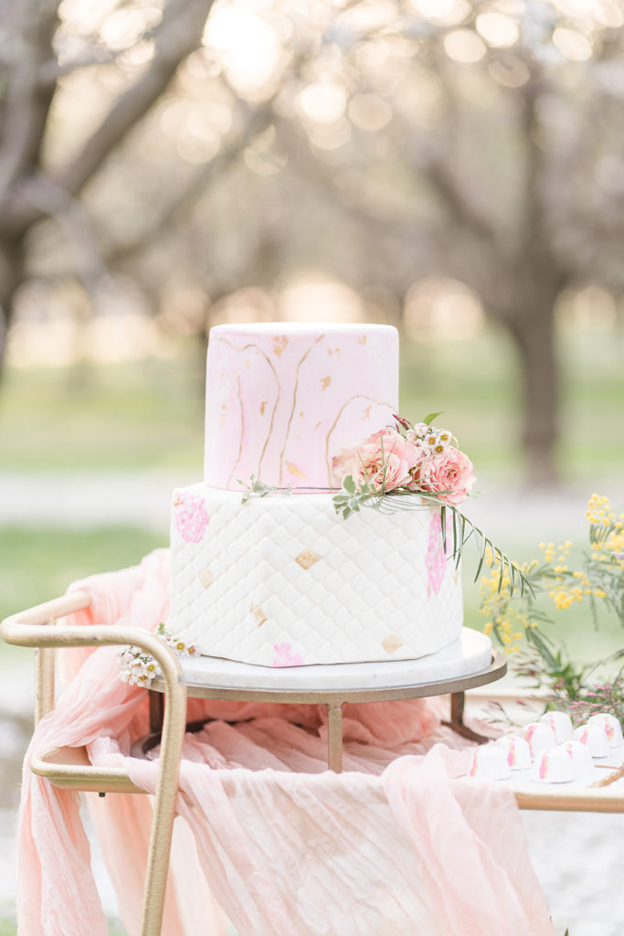 a wedding cake and dessert table in the almond blossoms