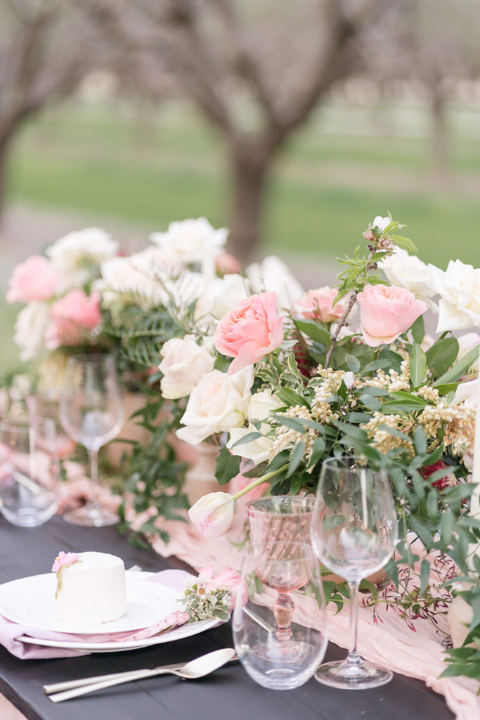 a wedding reception sweetheart table centerpiece nestled in the almond blossoms