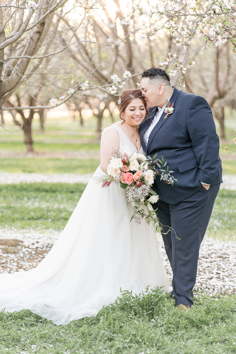 lgbt couple poses under the almond blossoms for their wedding portraits