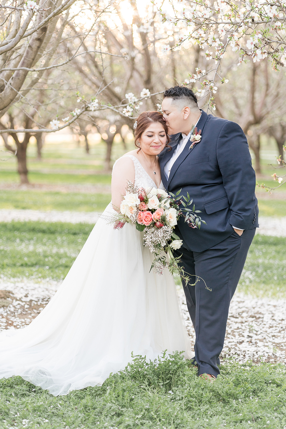 lgbt couple poses under the almond blossoms in woodland, ca