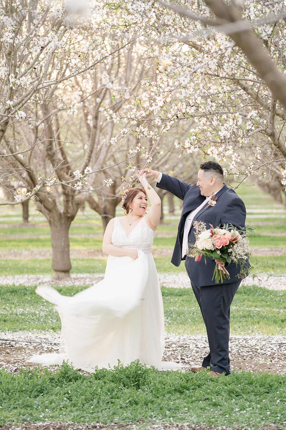 lgbt couple poses under the almond blossoms in woodland, ca