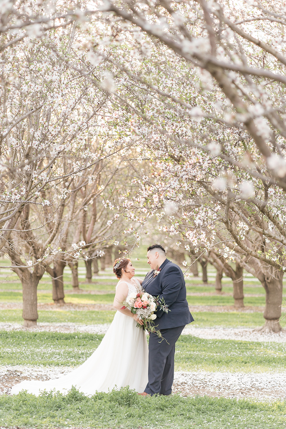 lgbt couple poses under the almond blossoms in woodland, ca