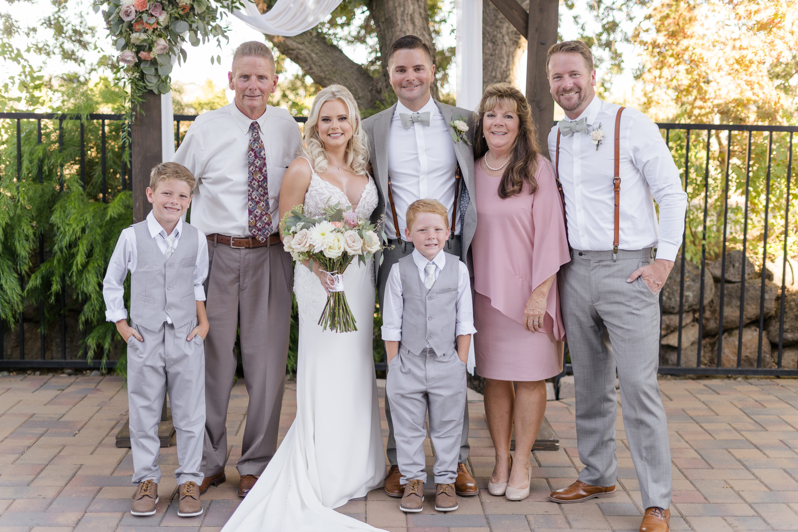a bride and groom pose with the grooms parents, brother, and nephews for a  a wedding day family portrait by adrienne and dani photography, Napa Wedding Photographers