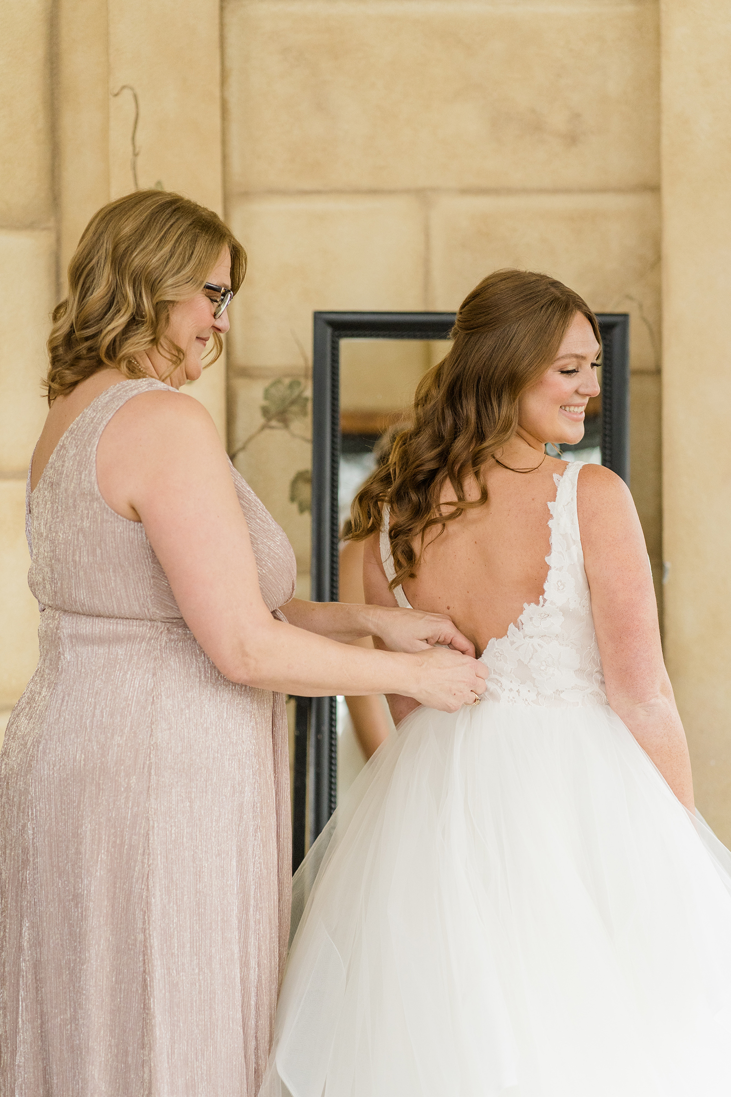 A mother of the bride helping her daughter prepare for her wedding at the Ridge Event Center by Adrienne and Dani Photography