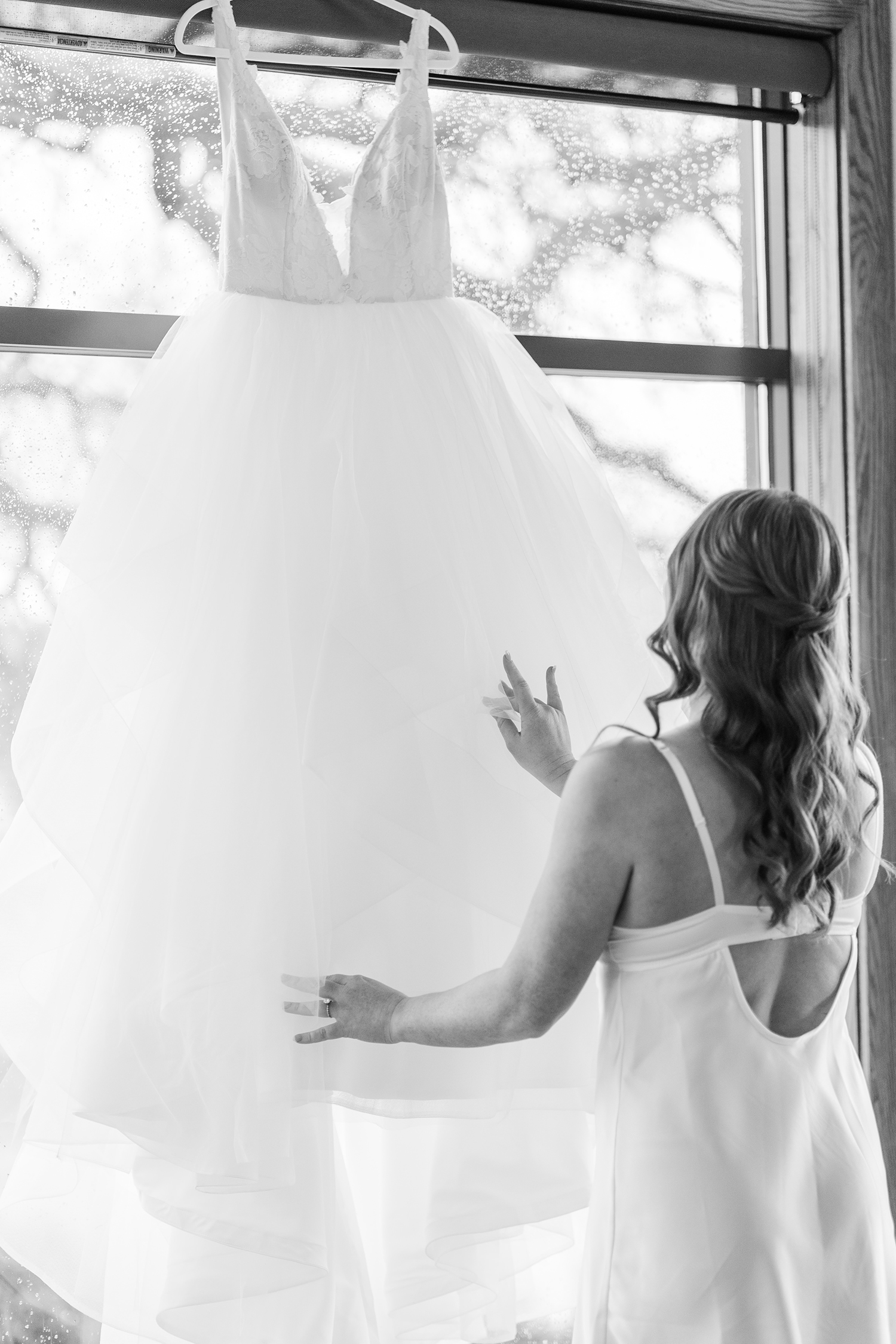 A bride admiring her wedding dress for a wedding at the Ridge Event Center by Adrienne and Dani Photography