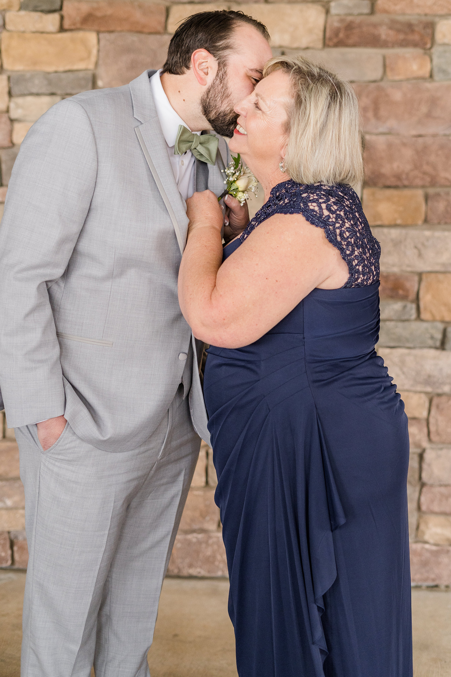 a grooms mother helping him prepare for his wedding at the Ridge Event Center by Adrienne and Dani Photography