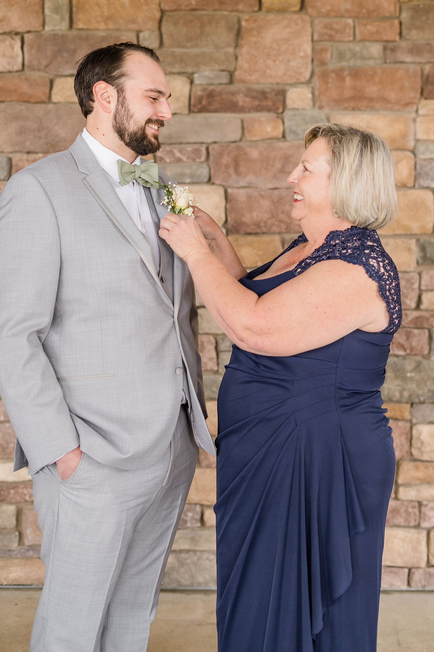 a grooms mother helping him prepare for his wedding at the Ridge Event Center by Adrienne and Dani Photography