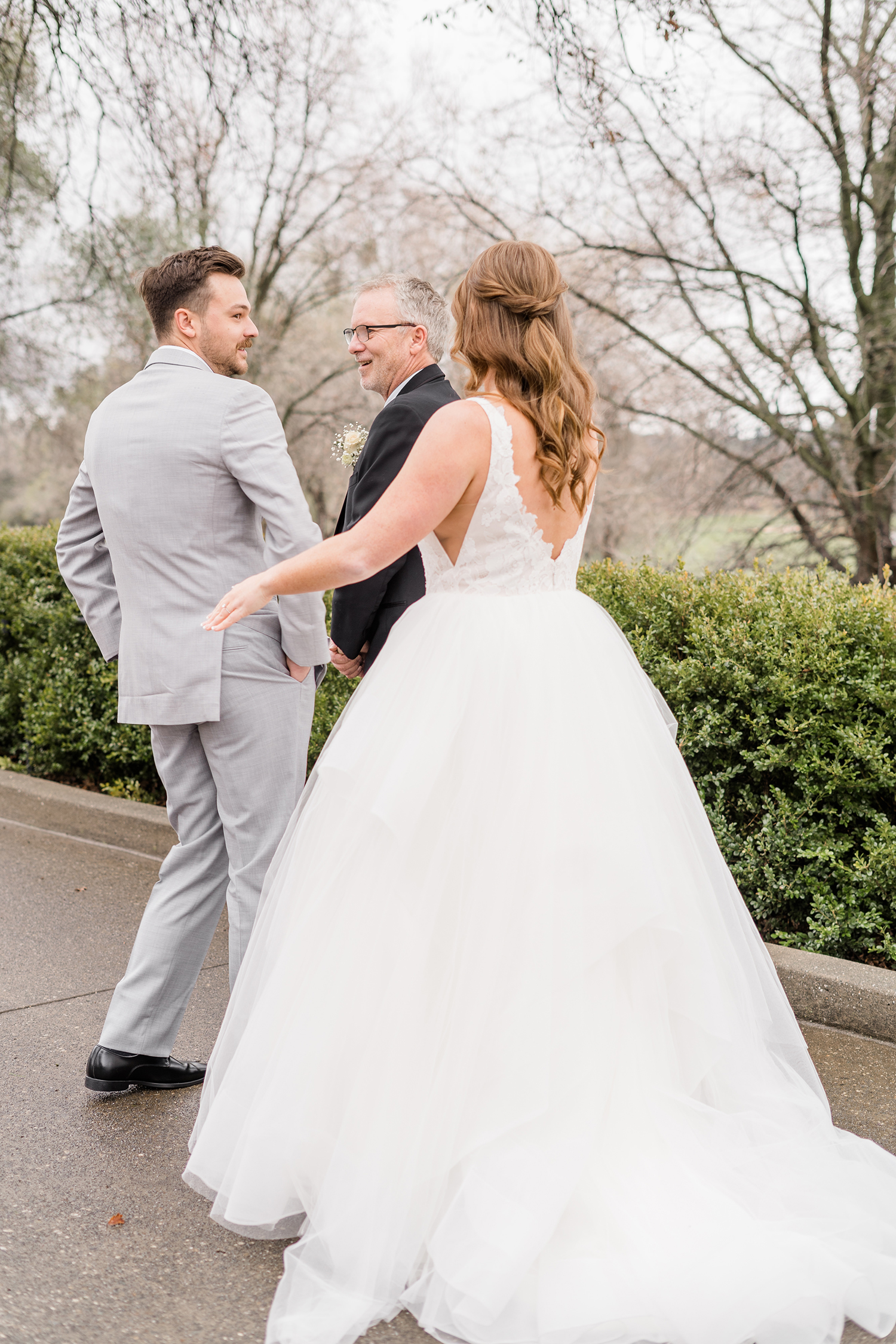 a bride shares a first look with her father and brother at her wedding at the Ridge Event Center by Adrienne and Dani Photography