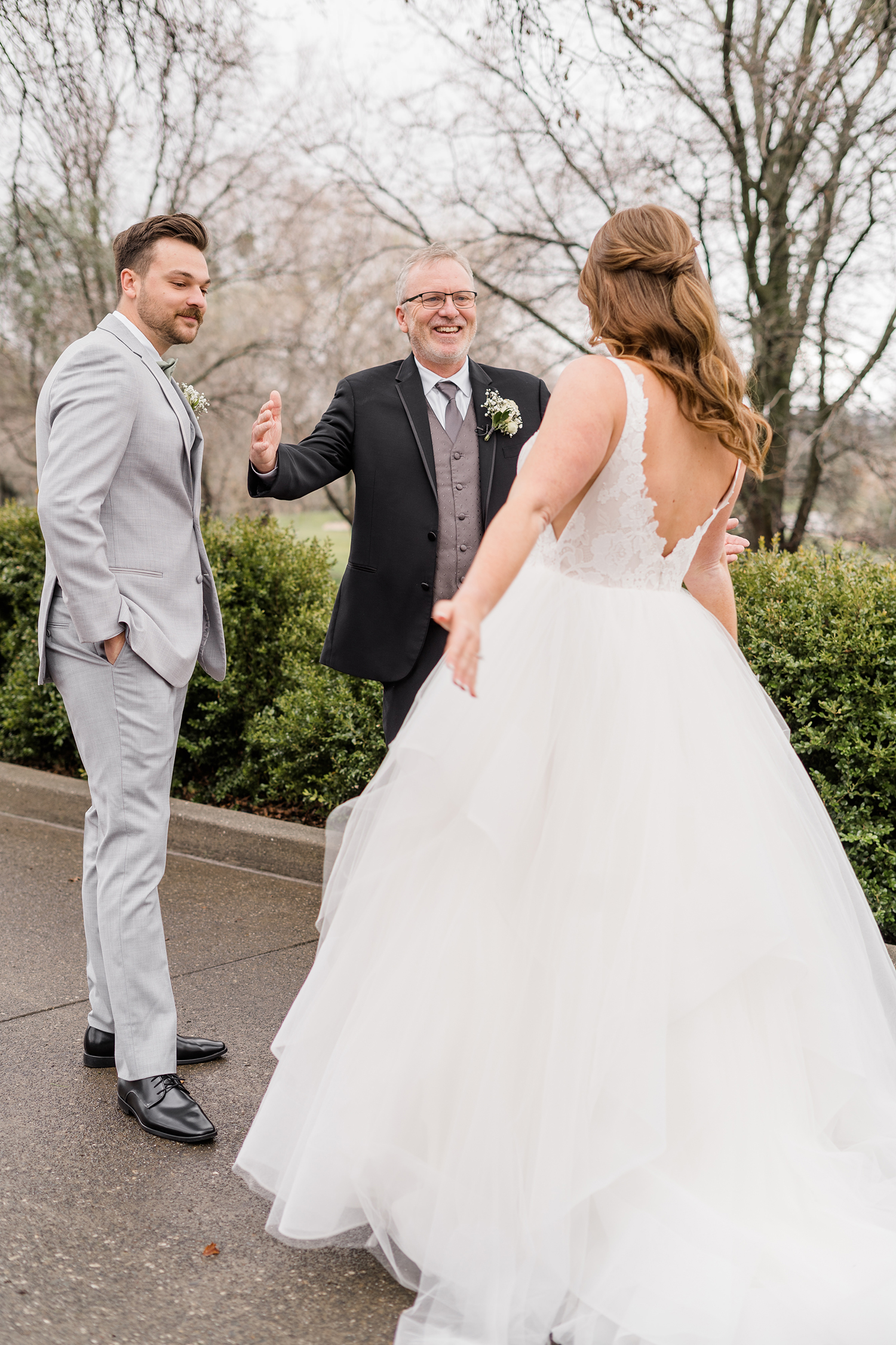 a bride shares a first look with her father and brother at her wedding at the Ridge Event Center by Adrienne and Dani Photography