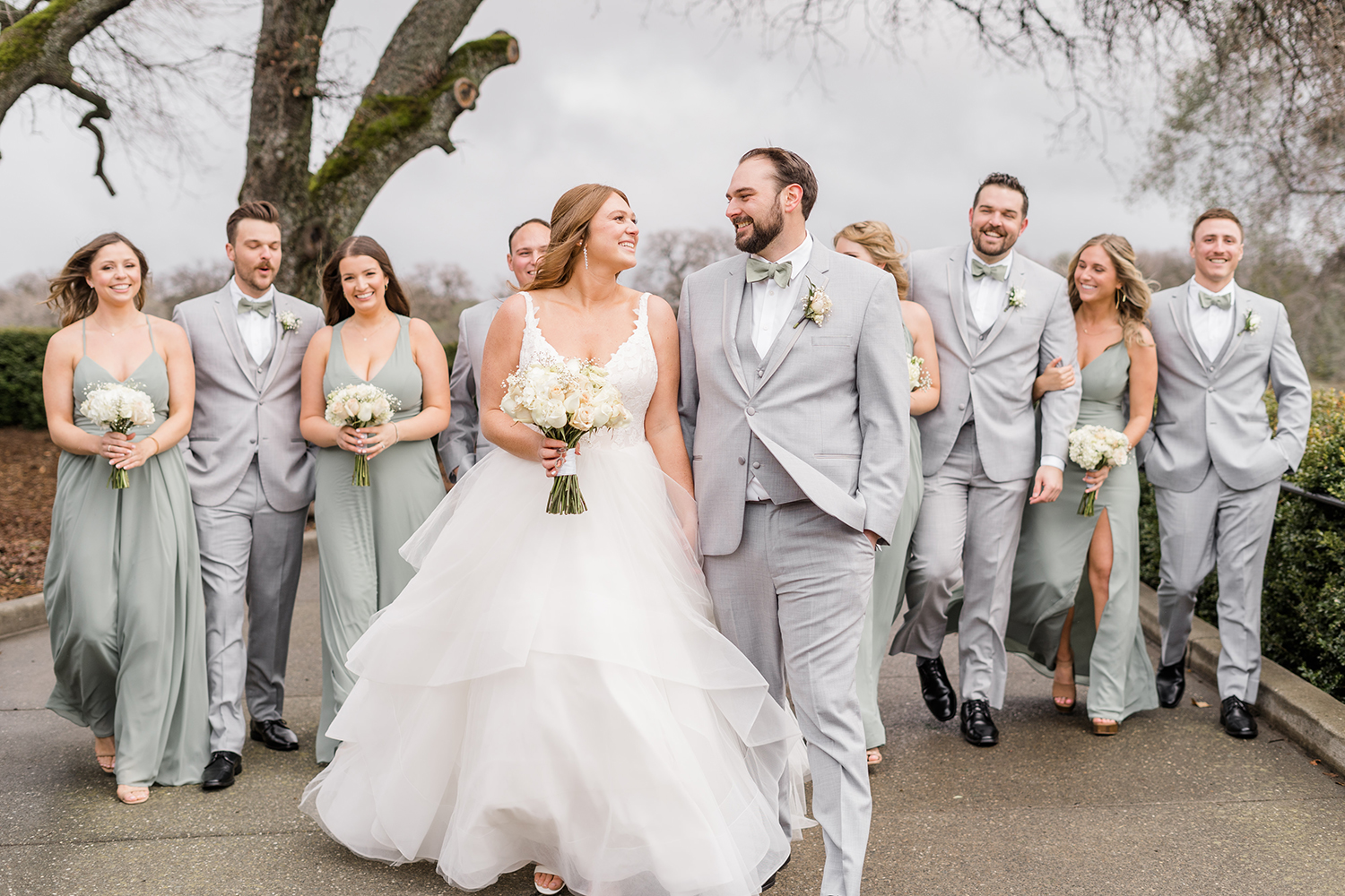 a wedding party in grey suits and sage green dresses at a wedding at the Ridge Event Center by Adrienne and Dani Photography