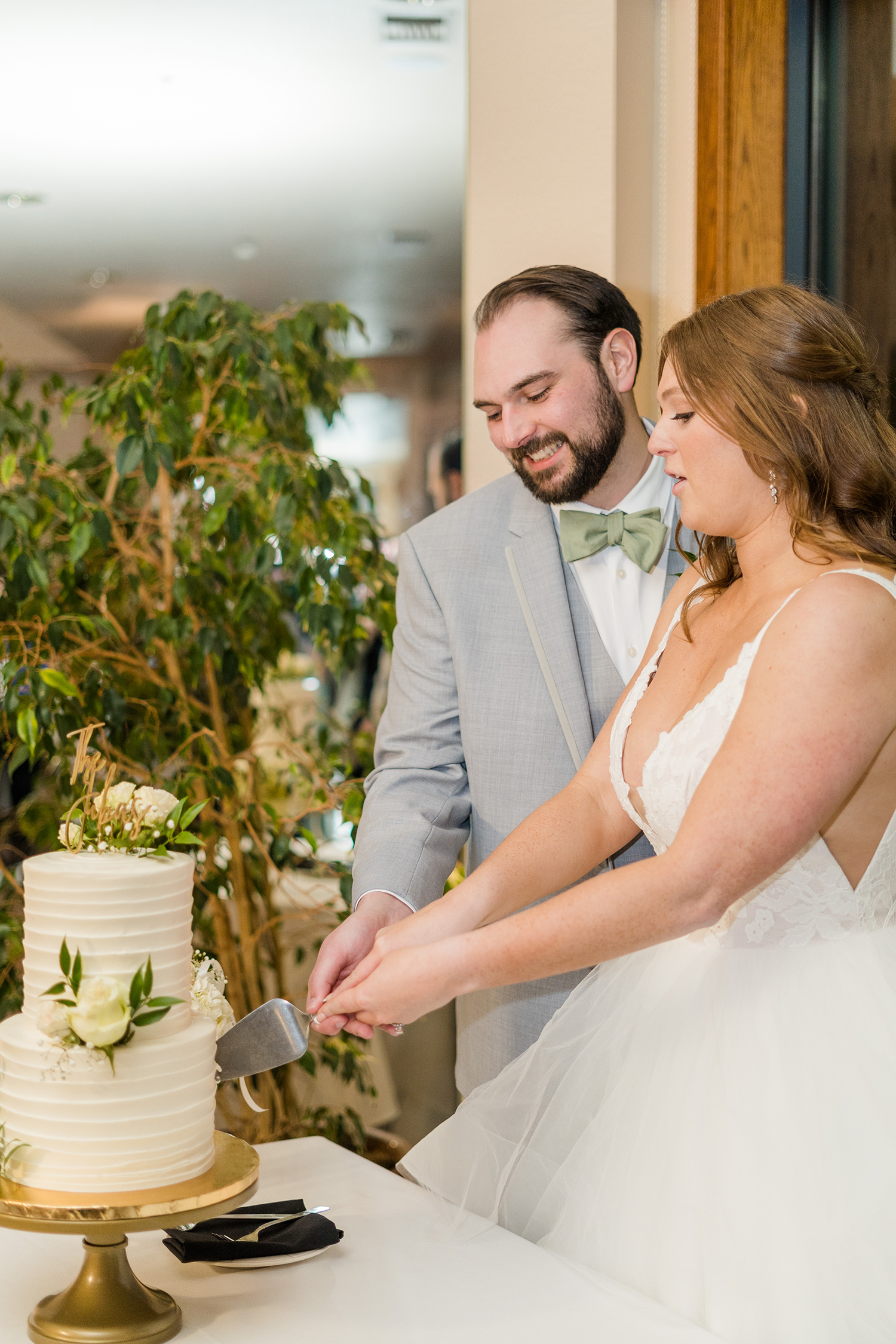 a bride and groom cut their wedding cake at the Ridge Event Center by Adrienne and Dani Photography