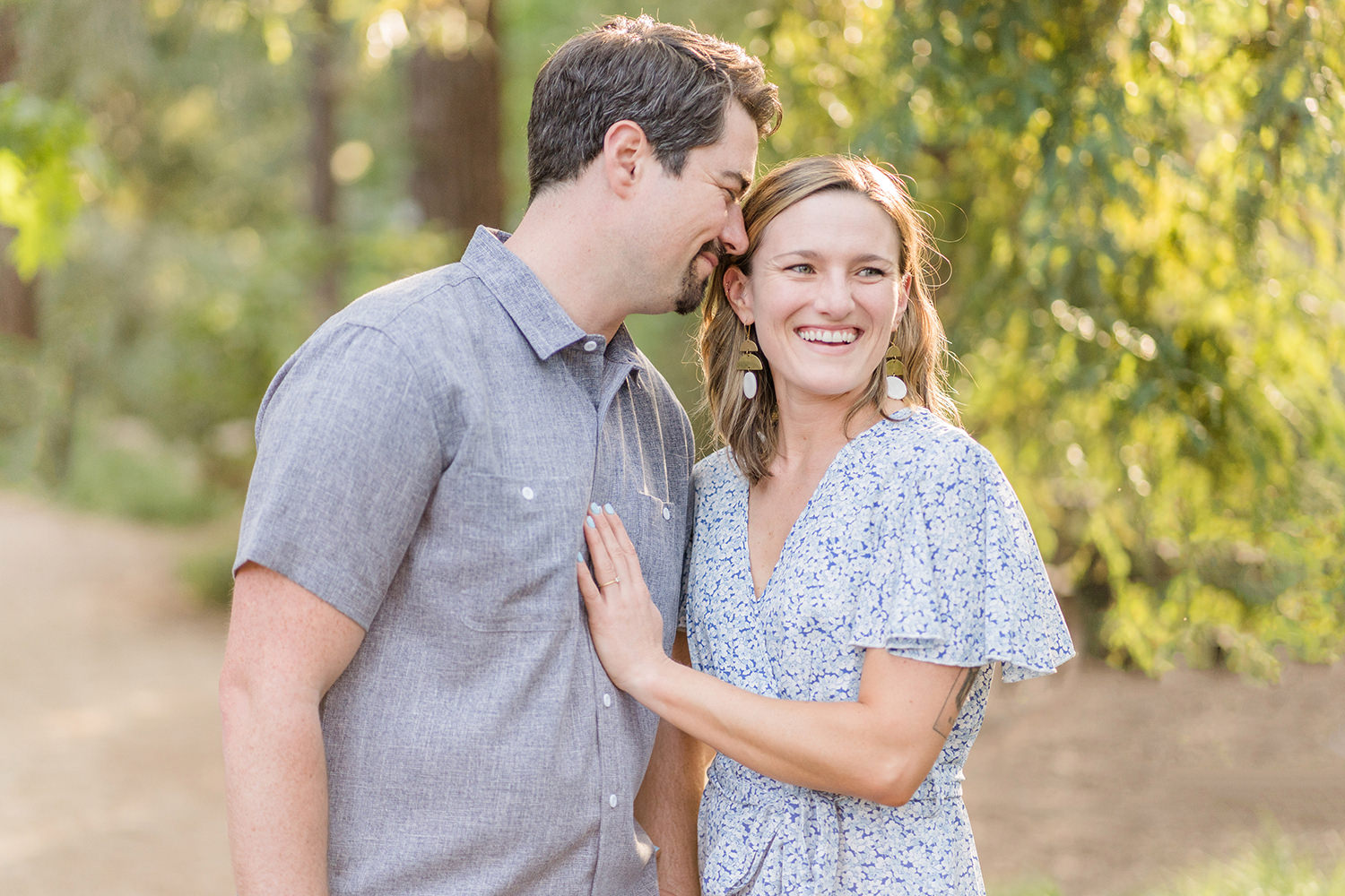 an engaged couple laughs together during their uc davis arboretum engagement session in the redwood grove