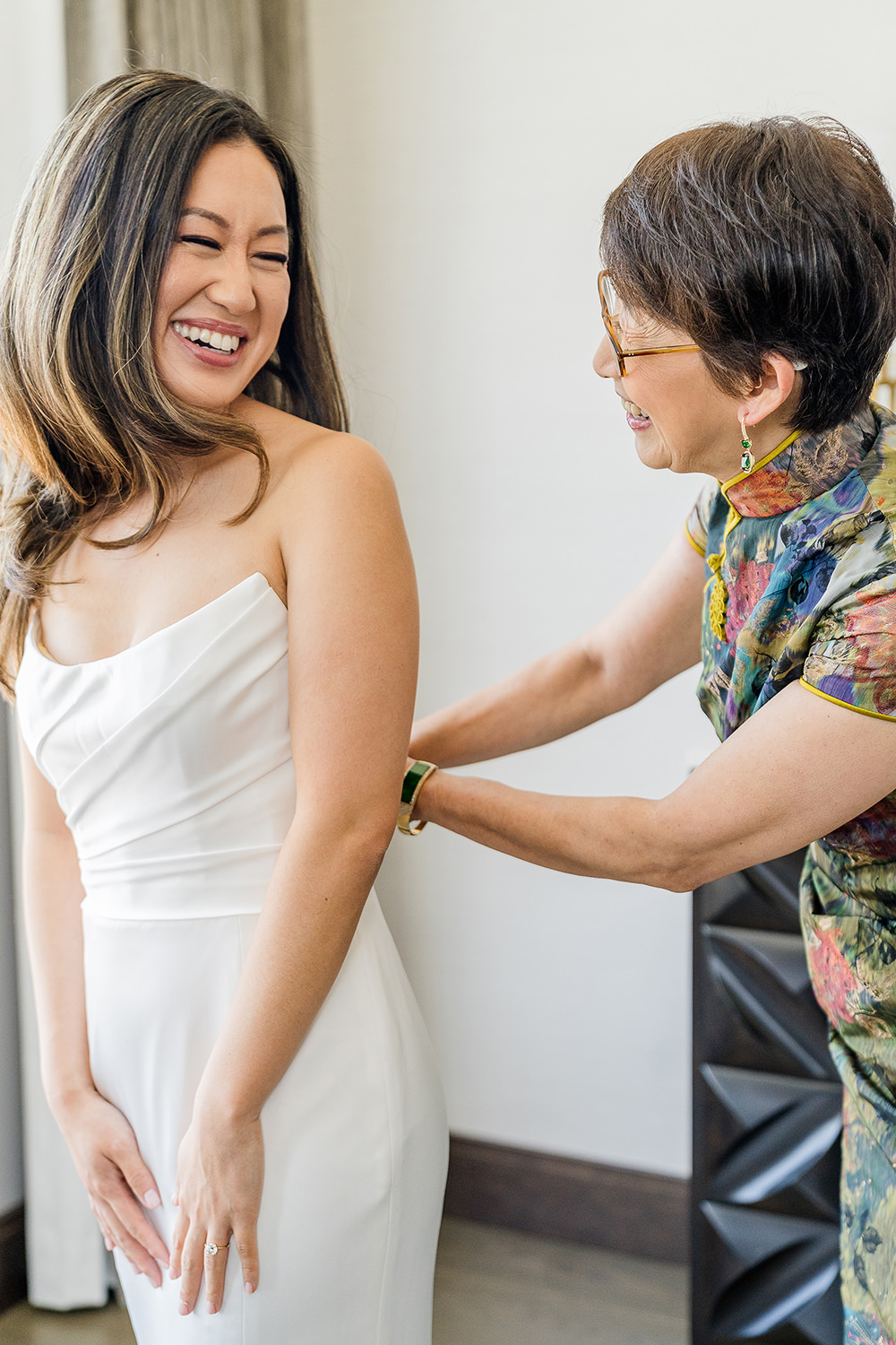 A bride laughs with her mom as she gets into her wedding dress at her Piedmont Park Wedding