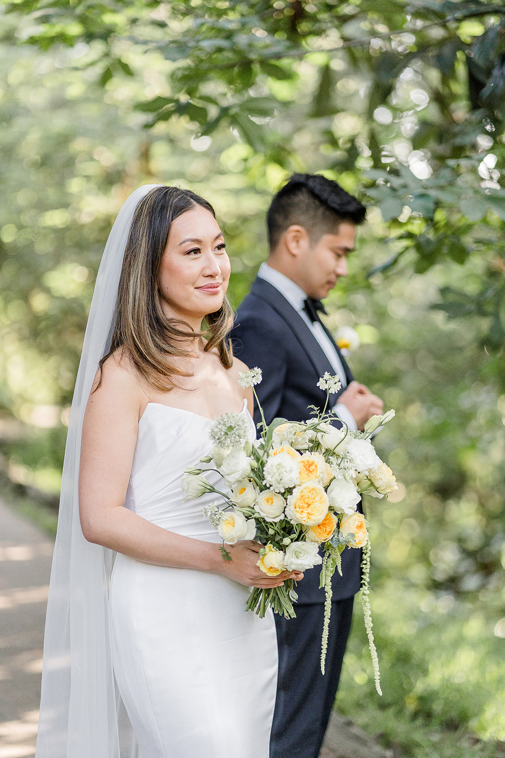 A bride looks on to her Piedmont Park Wedding ceremony as her groom adjusts his jacket