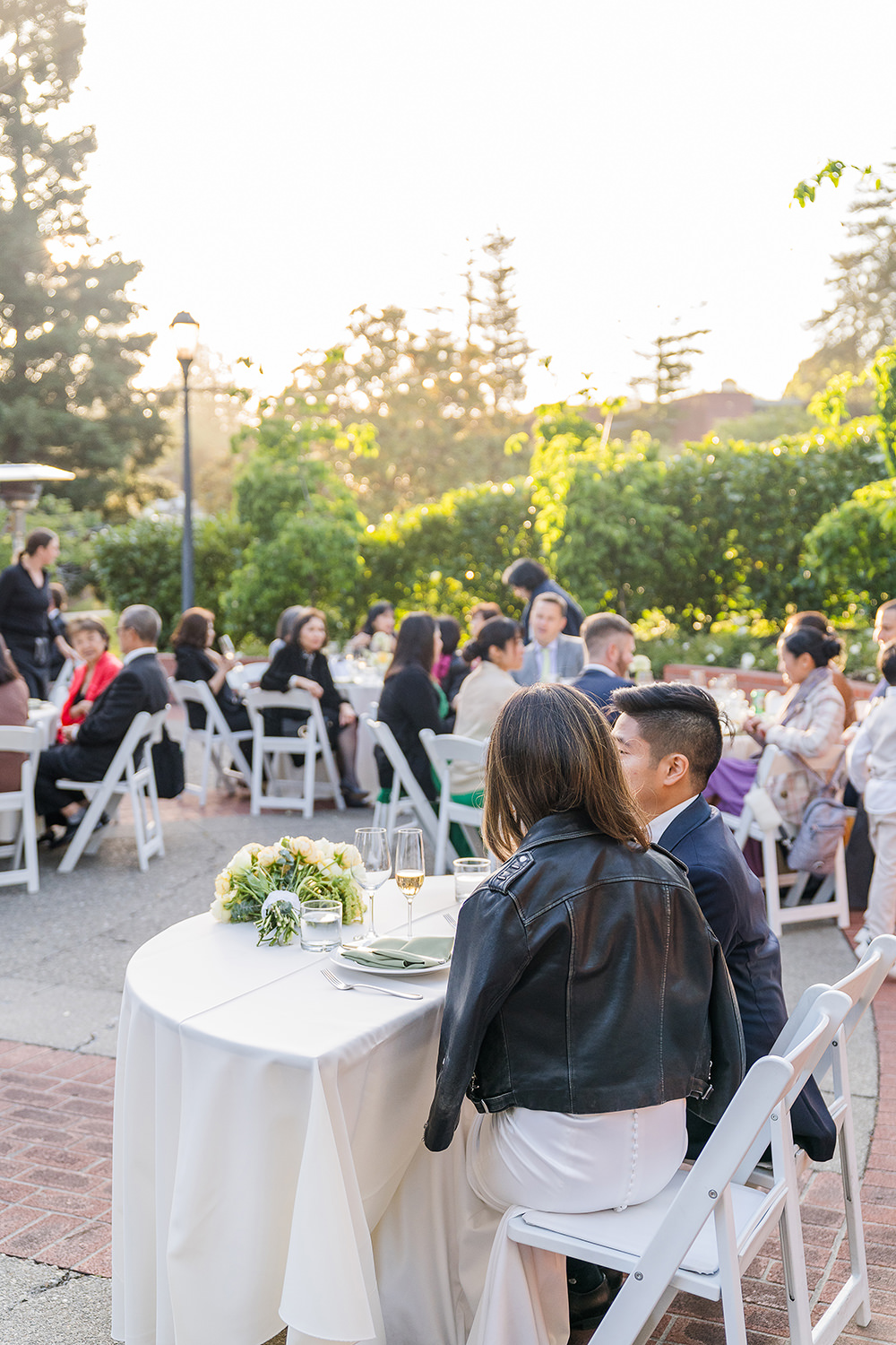 a Piedmont Park Wedding bride and groom sit at their sweetheart table looking on to their reception guests