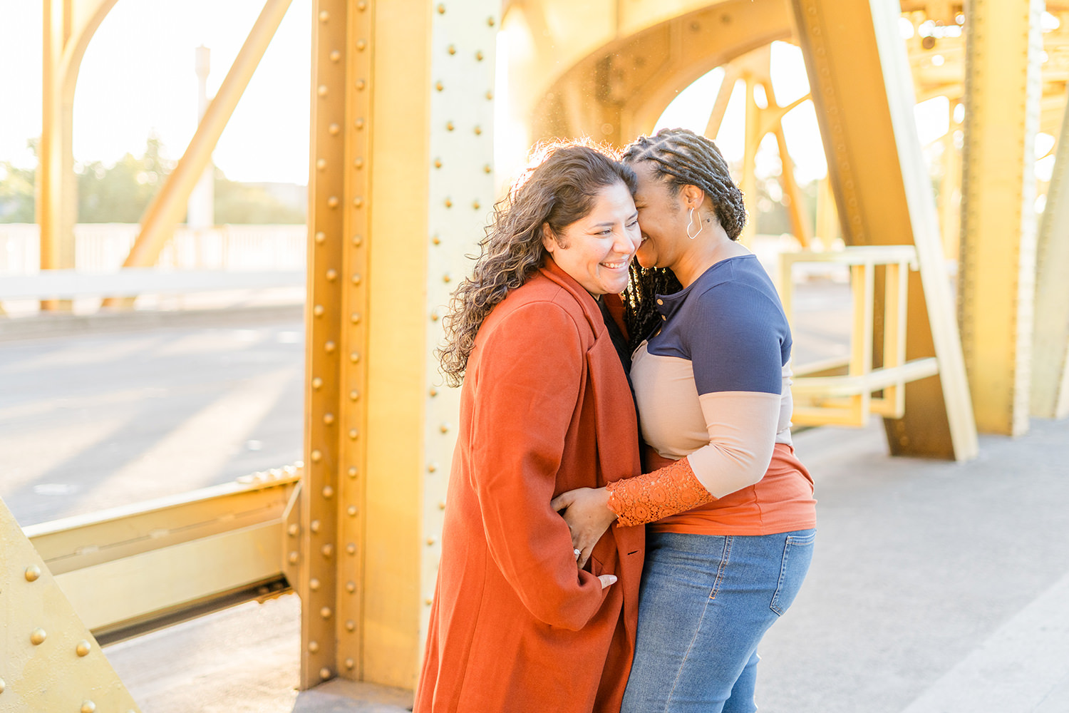 a lgbt lesbian couple snuggle up and laugh at their Downtown Sacramento LGBT Engagement Photos