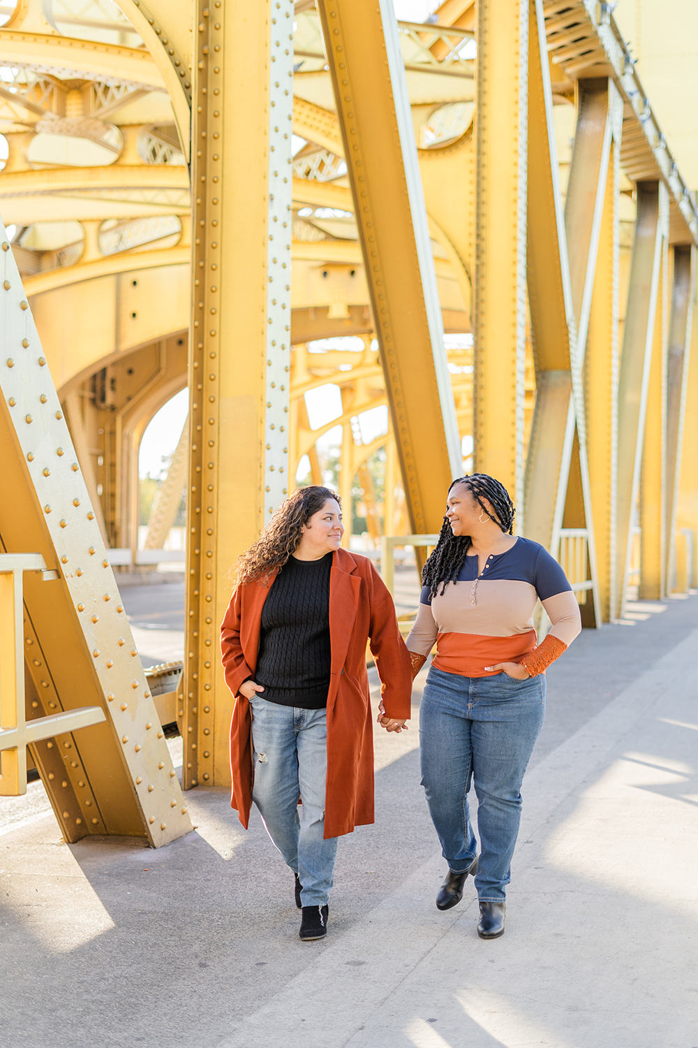 a lgbt lesbian couple hold hands as they walk along the tower bridge at their Downtown Sacramento LGBT Engagement Photos