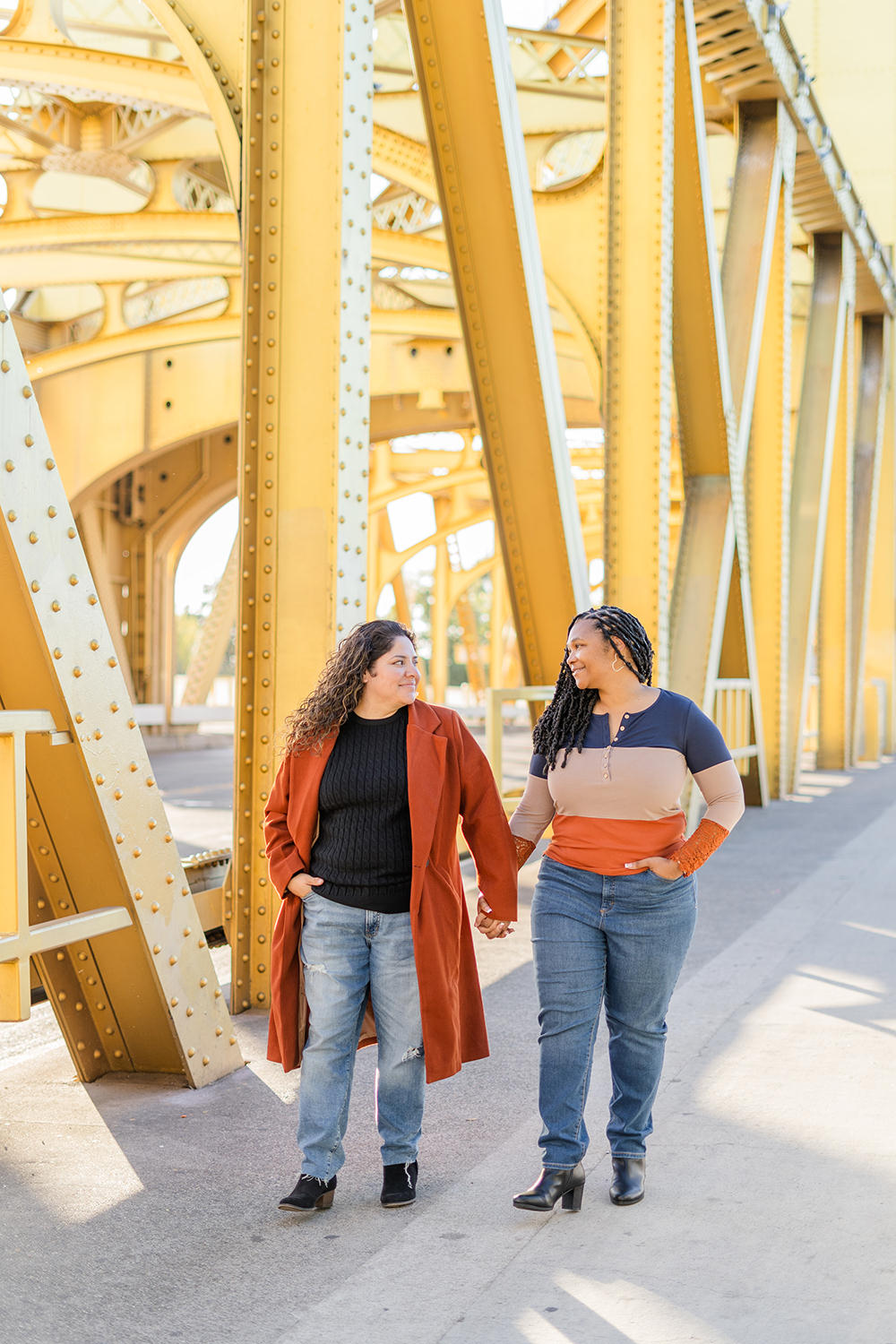 a lgbt lesbian couple hold hands as they walk along the tower bridge at their Downtown Sacramento LGBT Engagement Photos