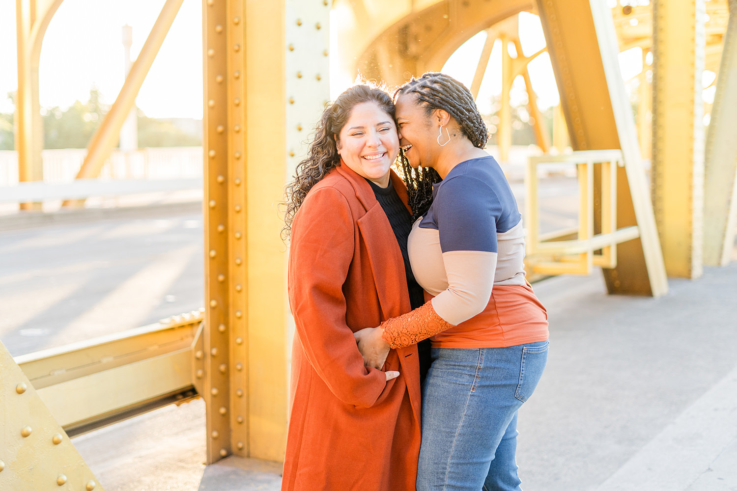 a lgbt lesbian couple snuggle up and laugh at their Downtown Sacramento LGBT Engagement Photos