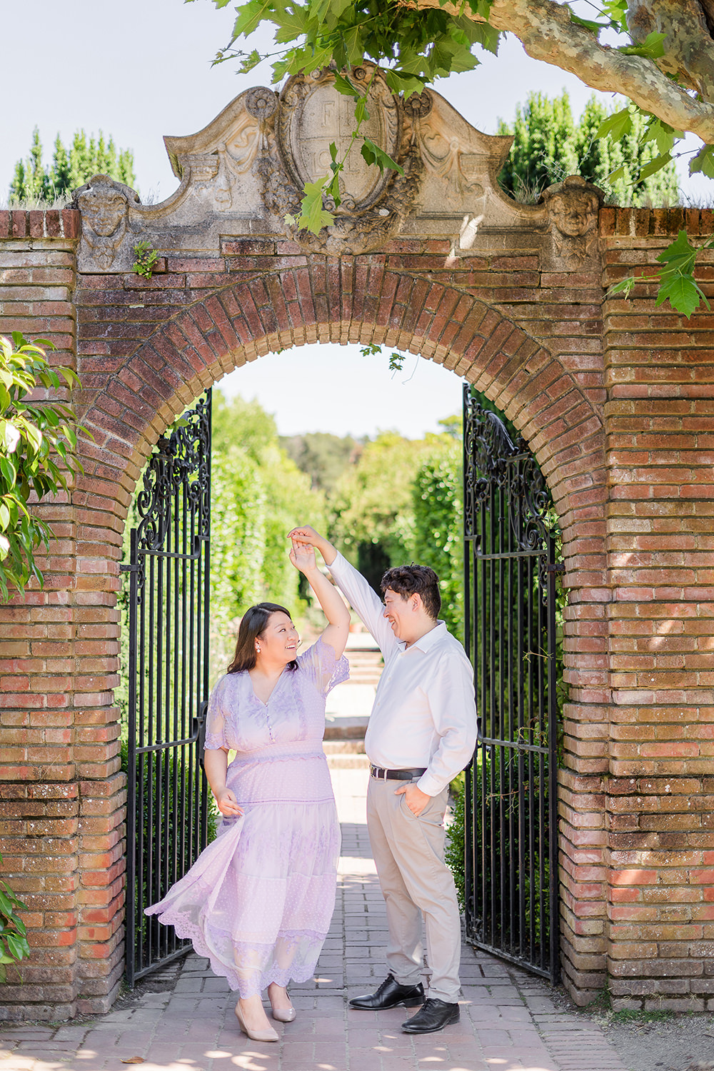 a bride and groom to-be dance together in front of a brick doorway for their filoli gardens engagement photos,