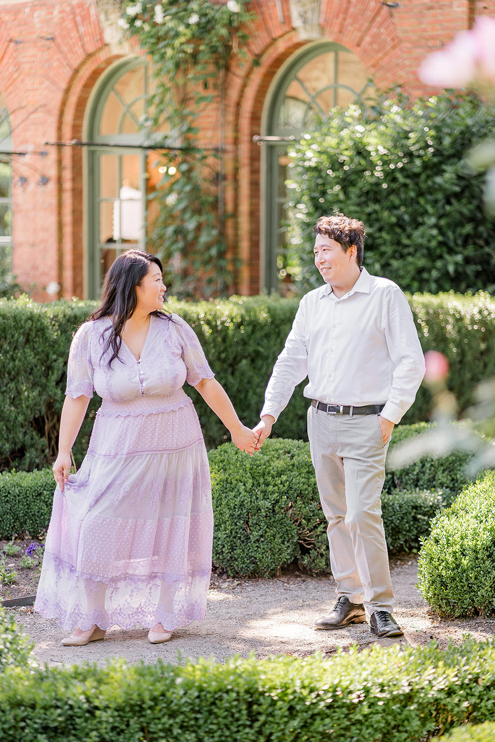 a bride and groom to be walk holding hands during their filoli gardens engagement photos.