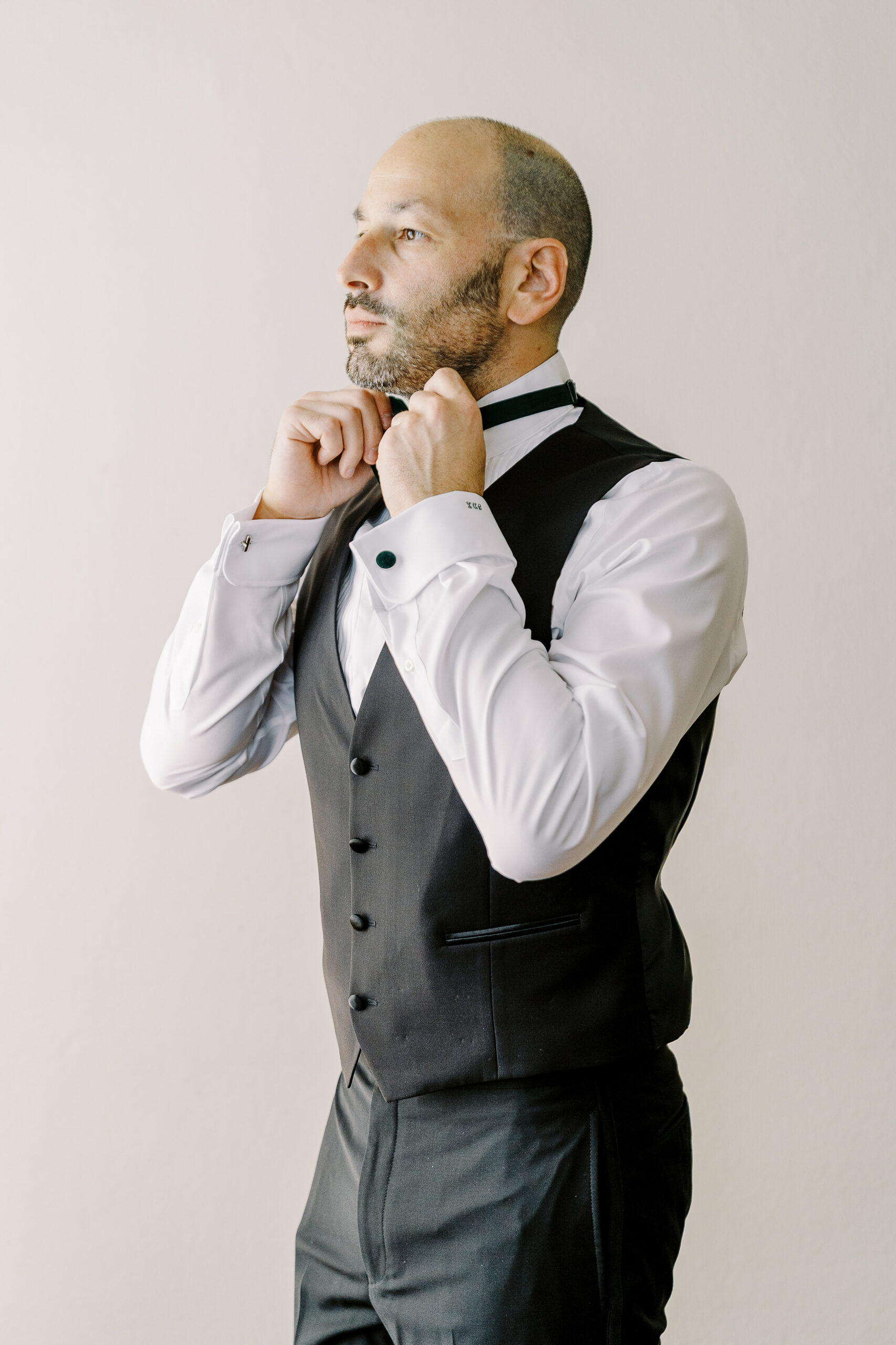 a groom adjusts his bow tie as he gets ready for his Downtown Sacramento Vizcaya Wedding