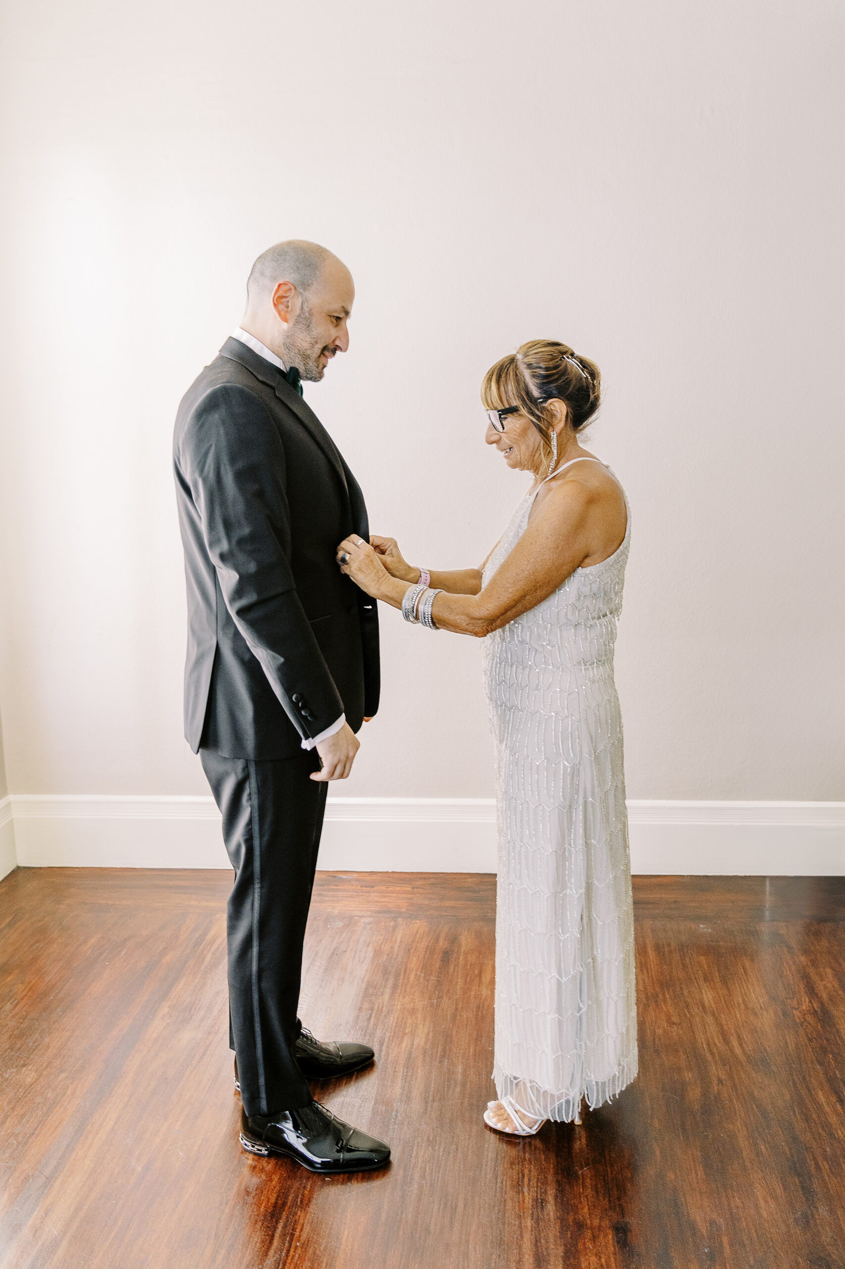 a groom's mother adjusts his jacket as he gets ready for his Downtown Sacramento Vizcaya Wedding