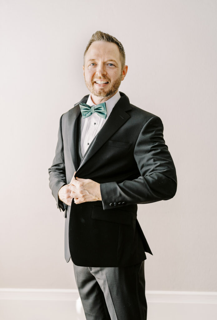 a groom buttons his jacket as he gets ready for his Downtown Sacramento Vizcaya Wedding