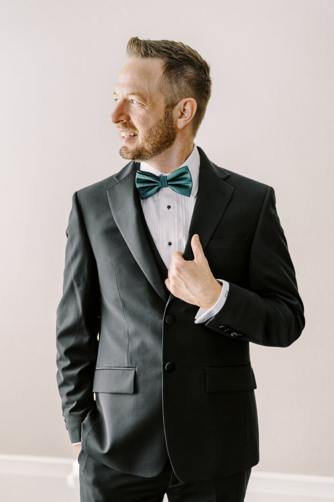 a groom adjusts his jacket as he gets ready for his Downtown Sacramento Vizcaya Wedding