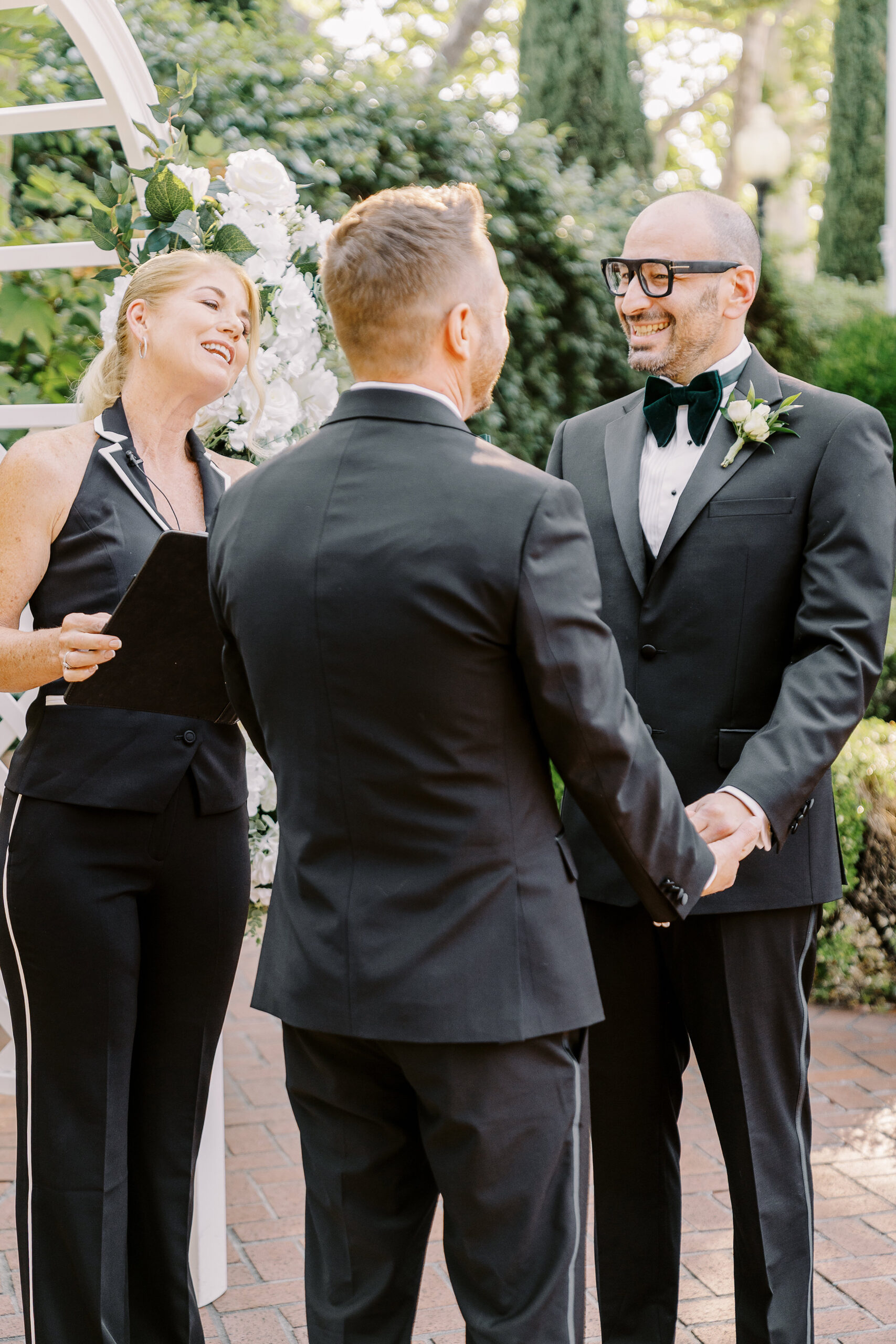 two grooms hold hands and laugh during their wedding ceremony at their Downtown Sacramento Vizcaya Wedding 