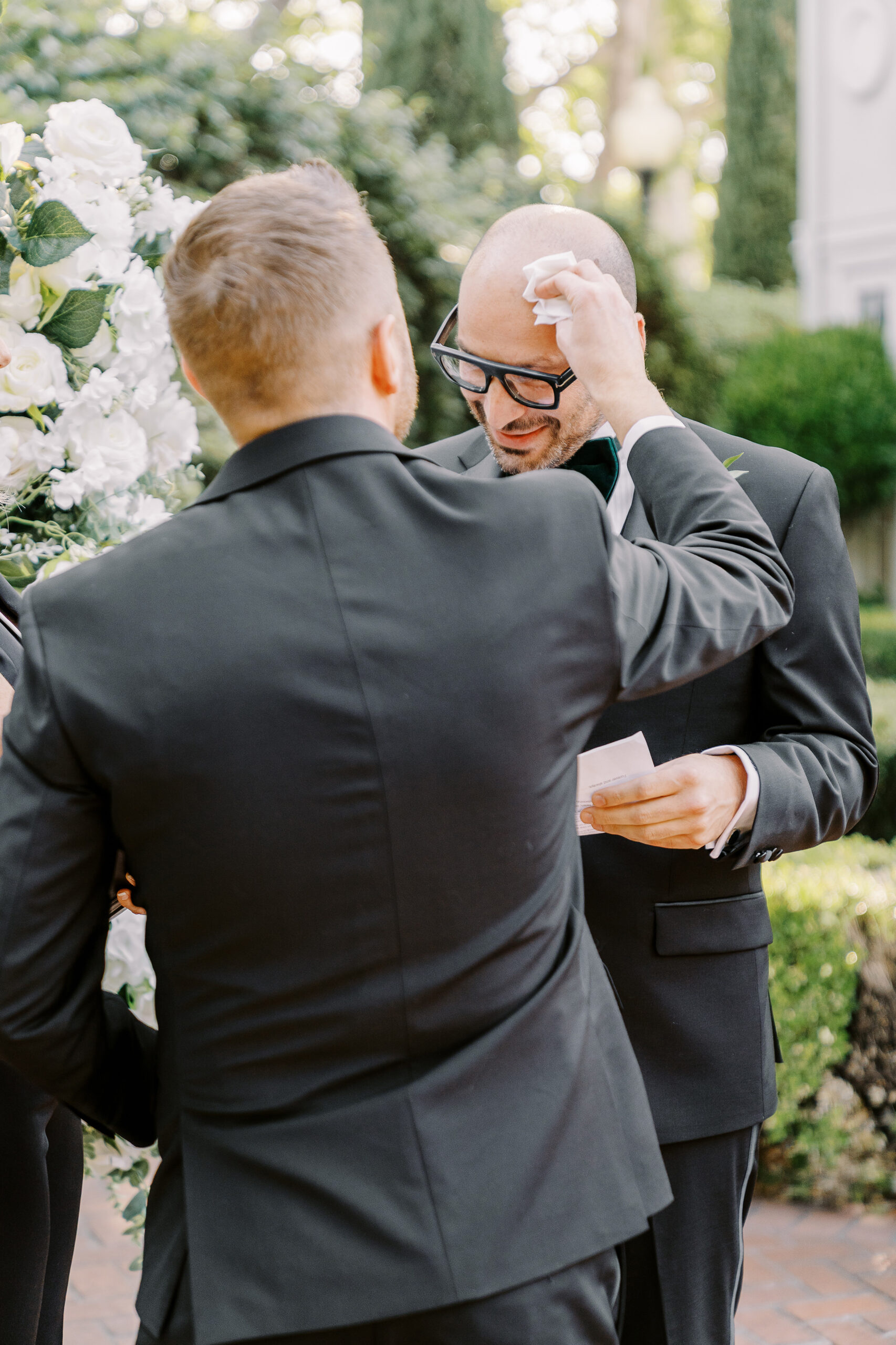 a groom wipes the sweat from his husbands brow during their wedding ceremony at their Downtown Sacramento Vizcaya Wedding 