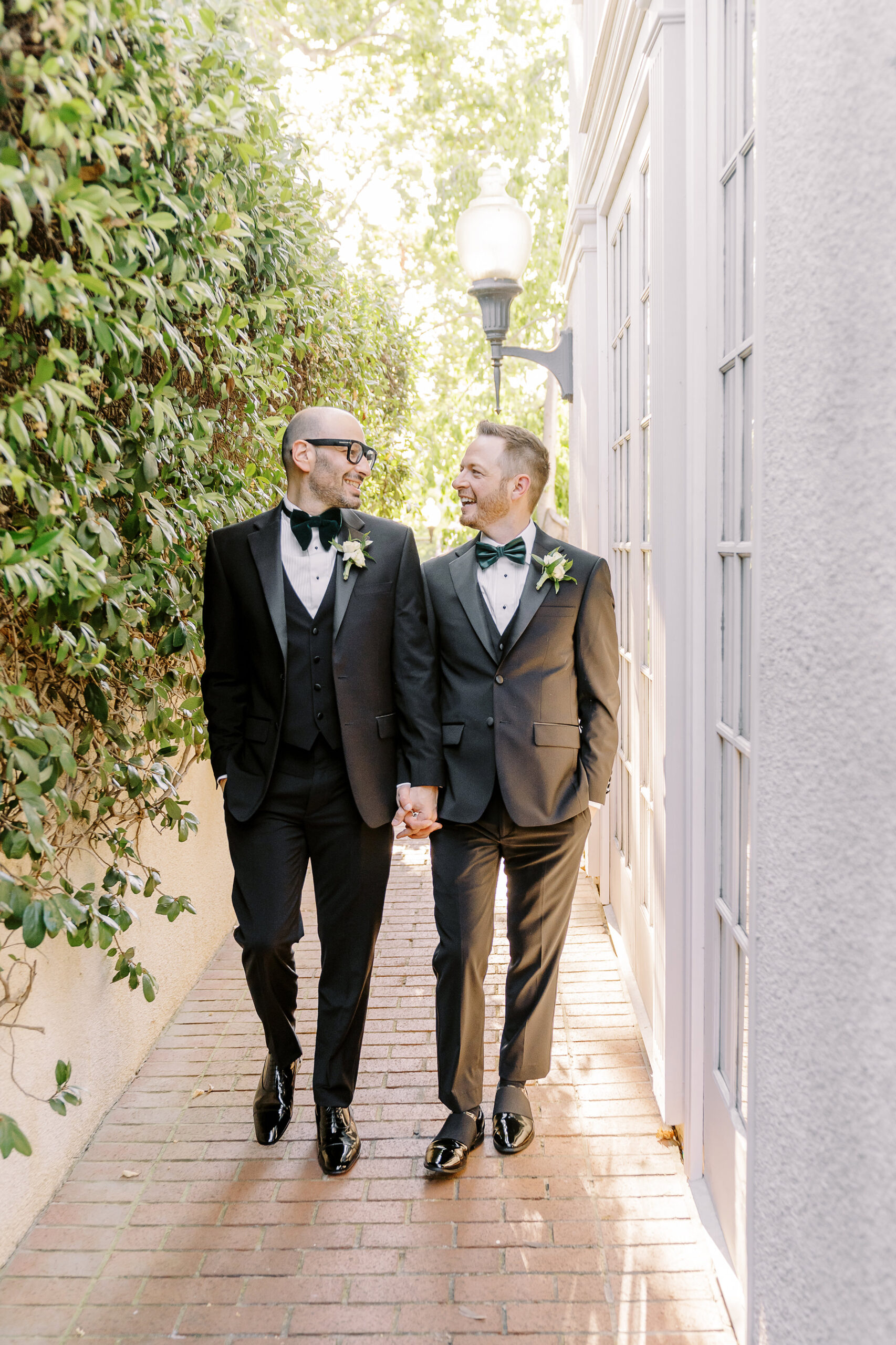 two grooms walk holding hands at their Downtown Sacramento Vizcaya Wedding 