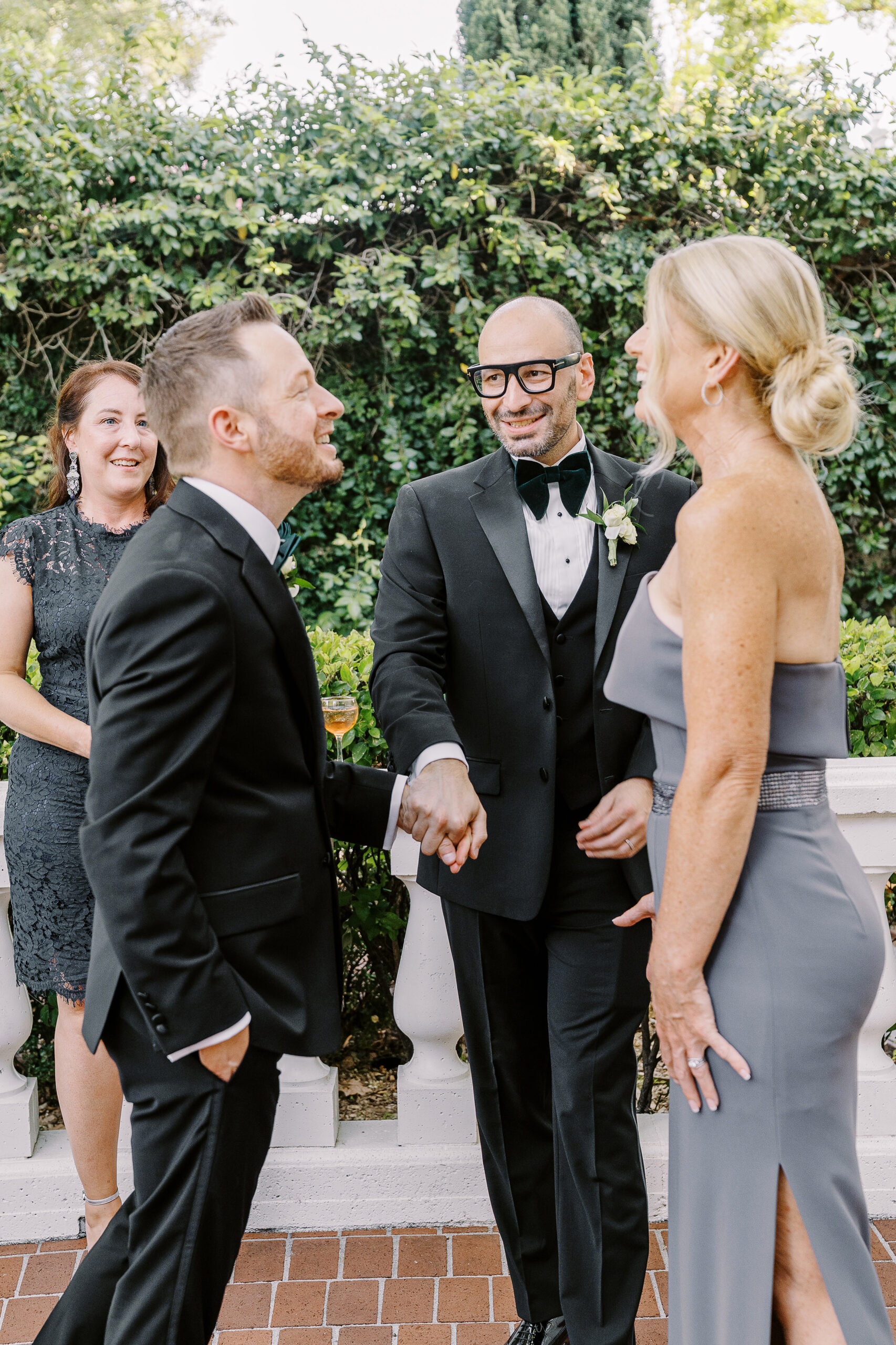 two grooms share a laugh while telling a story to their friends at their Downtown Sacramento Vizcaya Wedding 