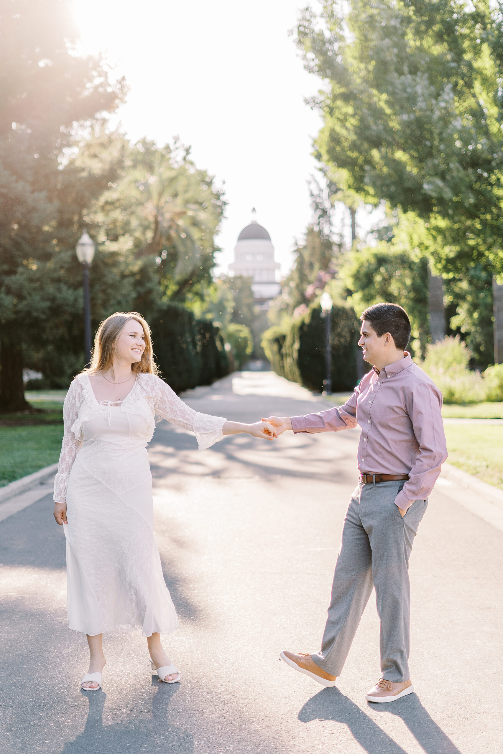 an engaged couple dances together in front of the Sacramento Capitol building for their Downtown Sacramento Capitol Engagement 