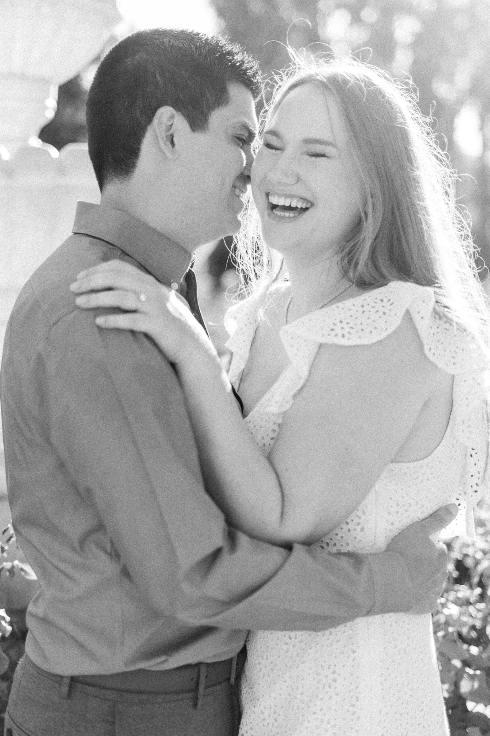 an engaged couple shares a laugh in the roses of the Downtown Sacramento Capitol rose garden