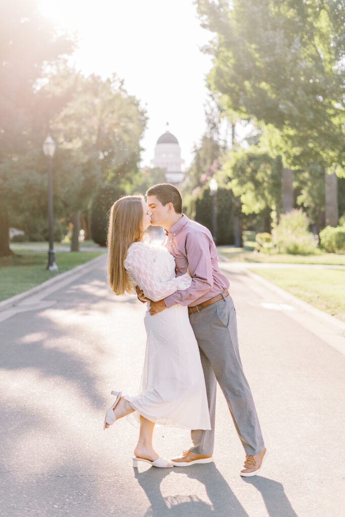 an engaged couple shares a kiss in front of the Sacramento Capitol building for their Downtown Sacramento Capitol Engagement 