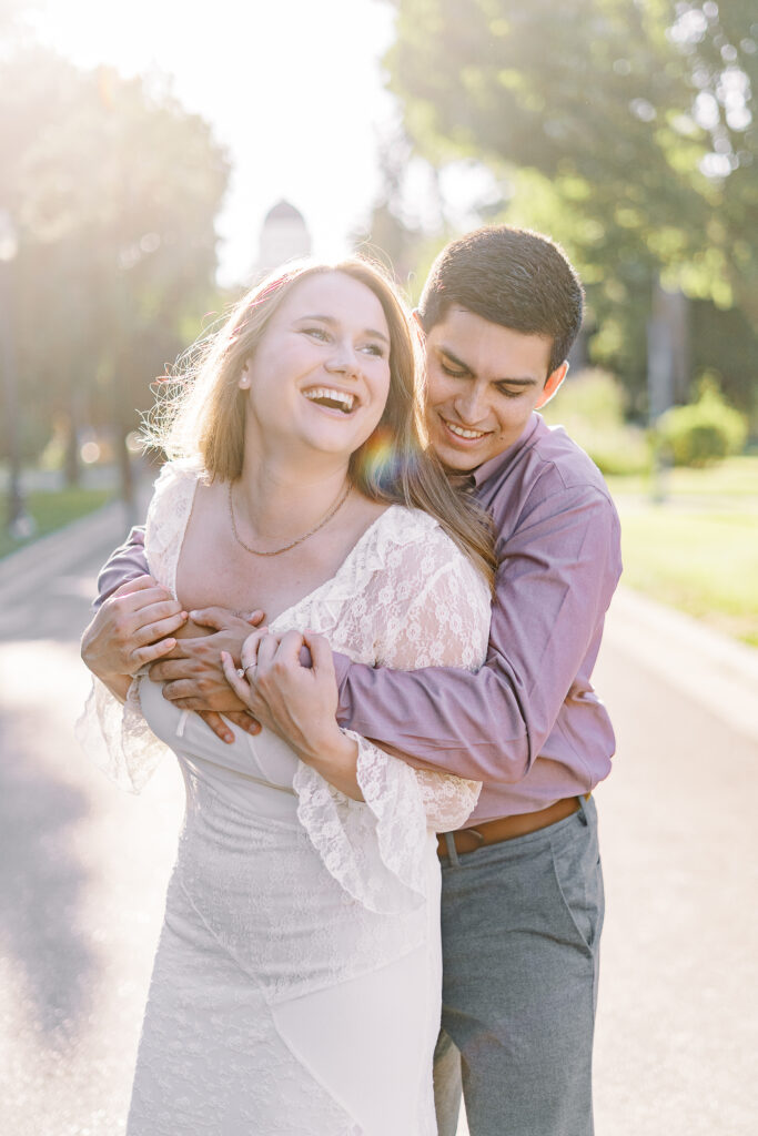 an engaged couple shares a hug in front of the Sacramento Capitol building for their Downtown Sacramento Capitol Engagement 