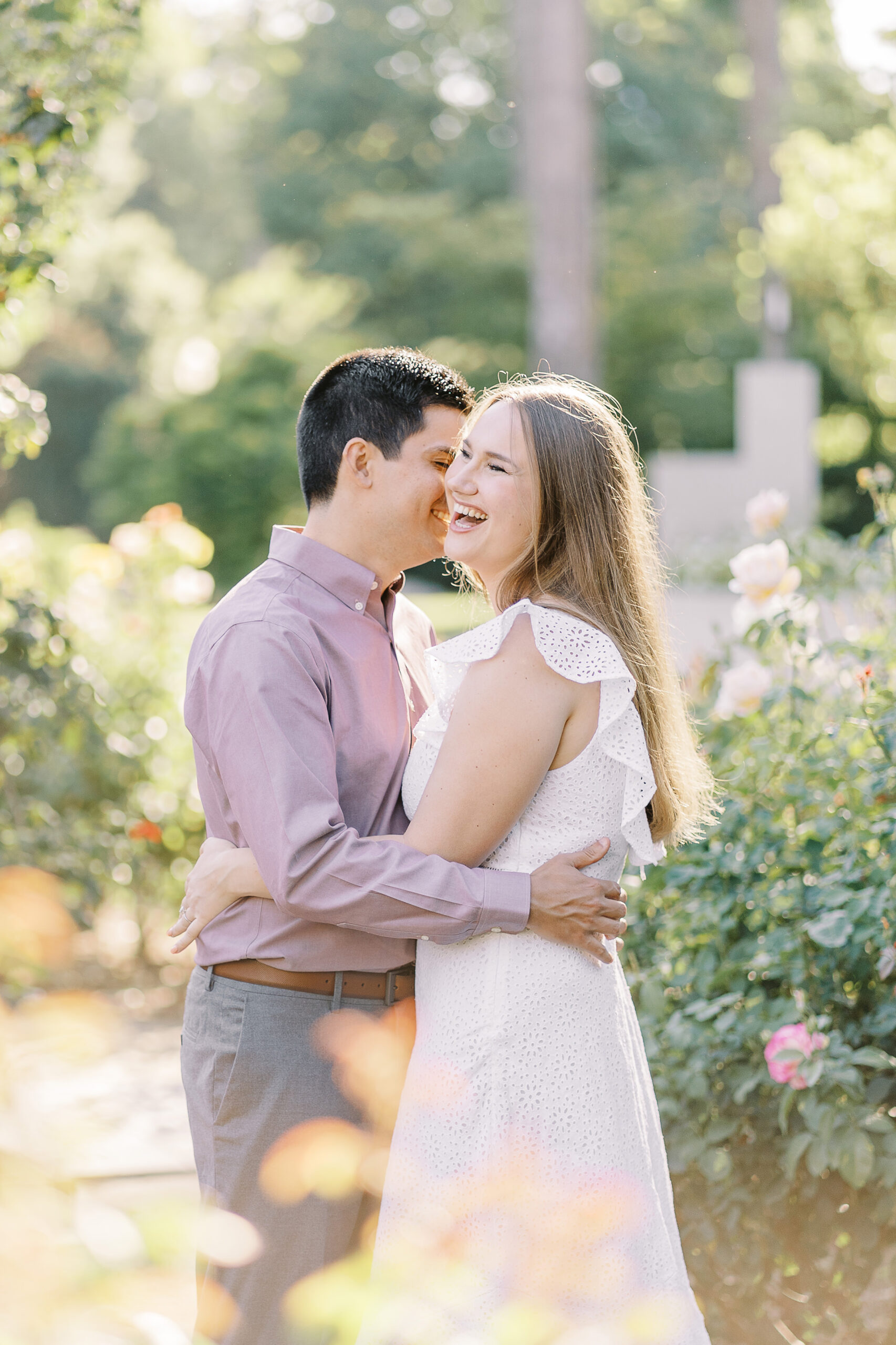 an engaged couple shares a laugh in the roses of the Downtown Sacramento Capitol rose garden