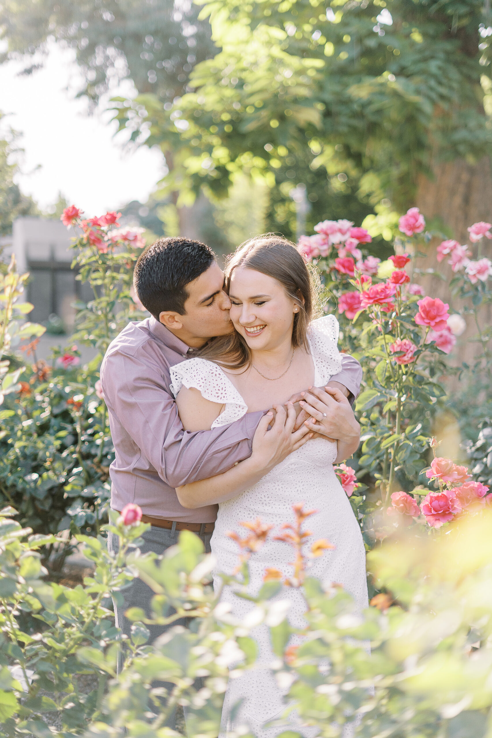 an engaged couple shares a hug in the roses of the Downtown Sacramento Capitol rose garden