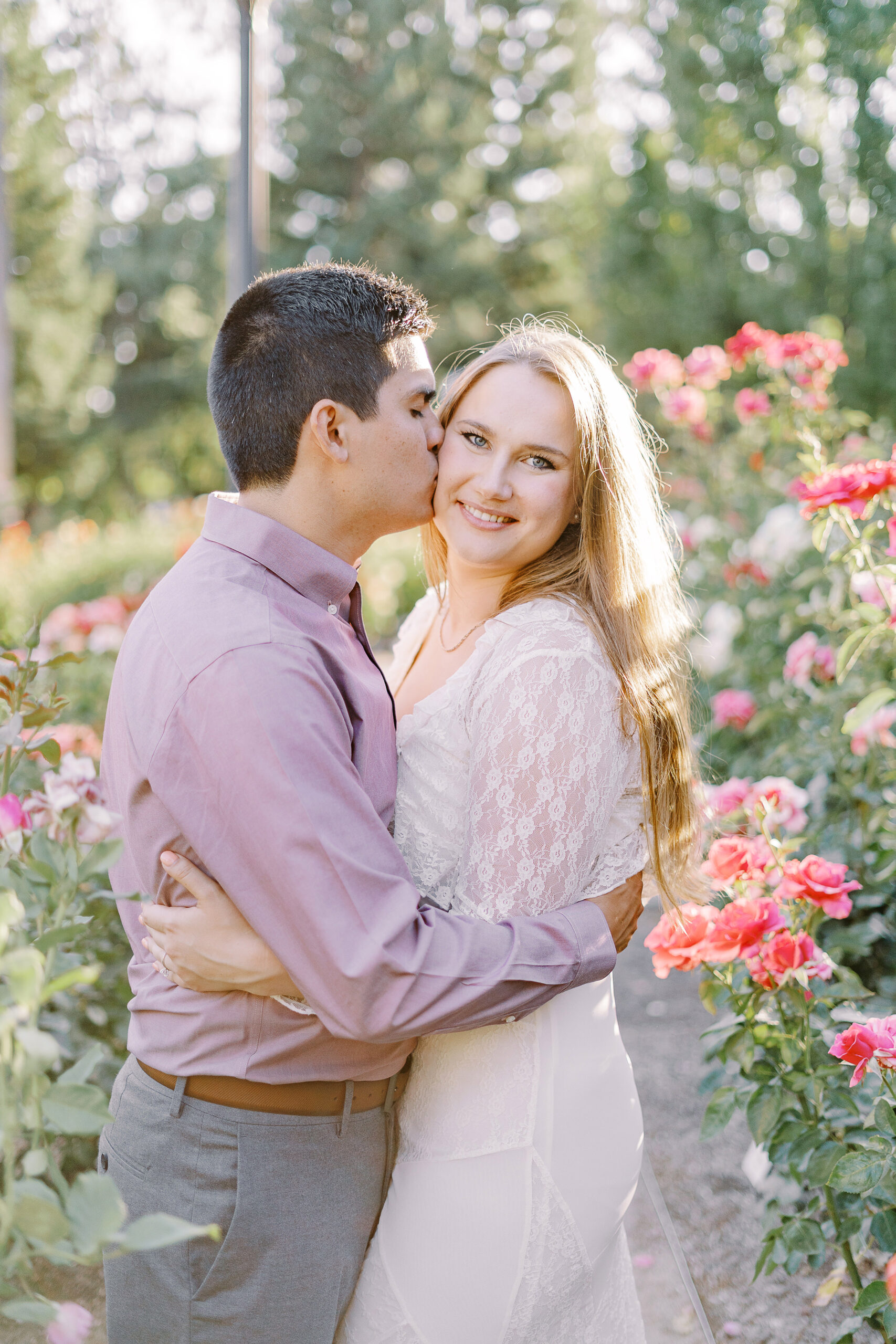 an engaged couple shares a hug in the roses of the Downtown Sacramento Capitol rose garden
