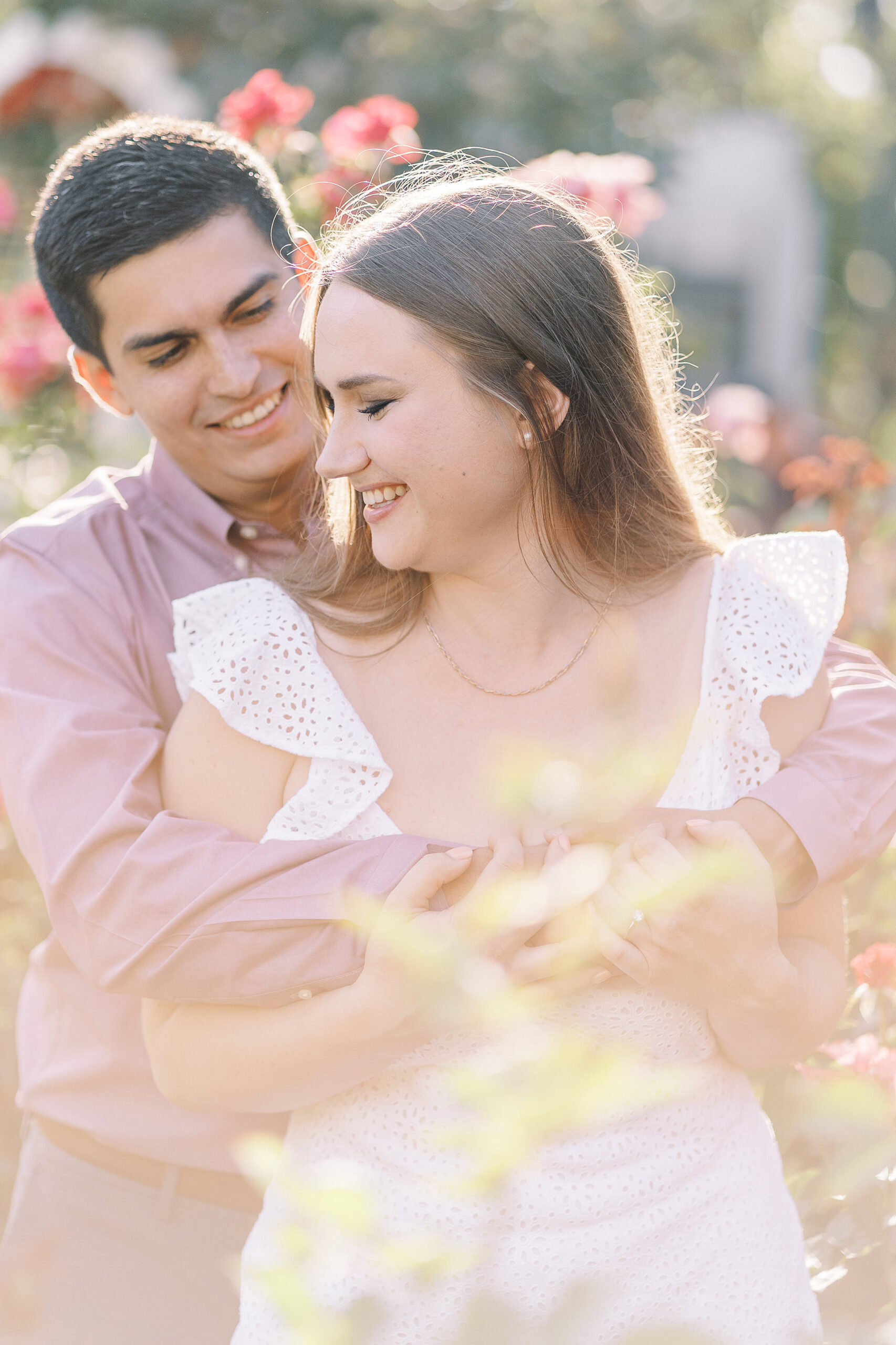an engaged couple shares a hug in the roses of the Downtown Sacramento Capitol rose garden