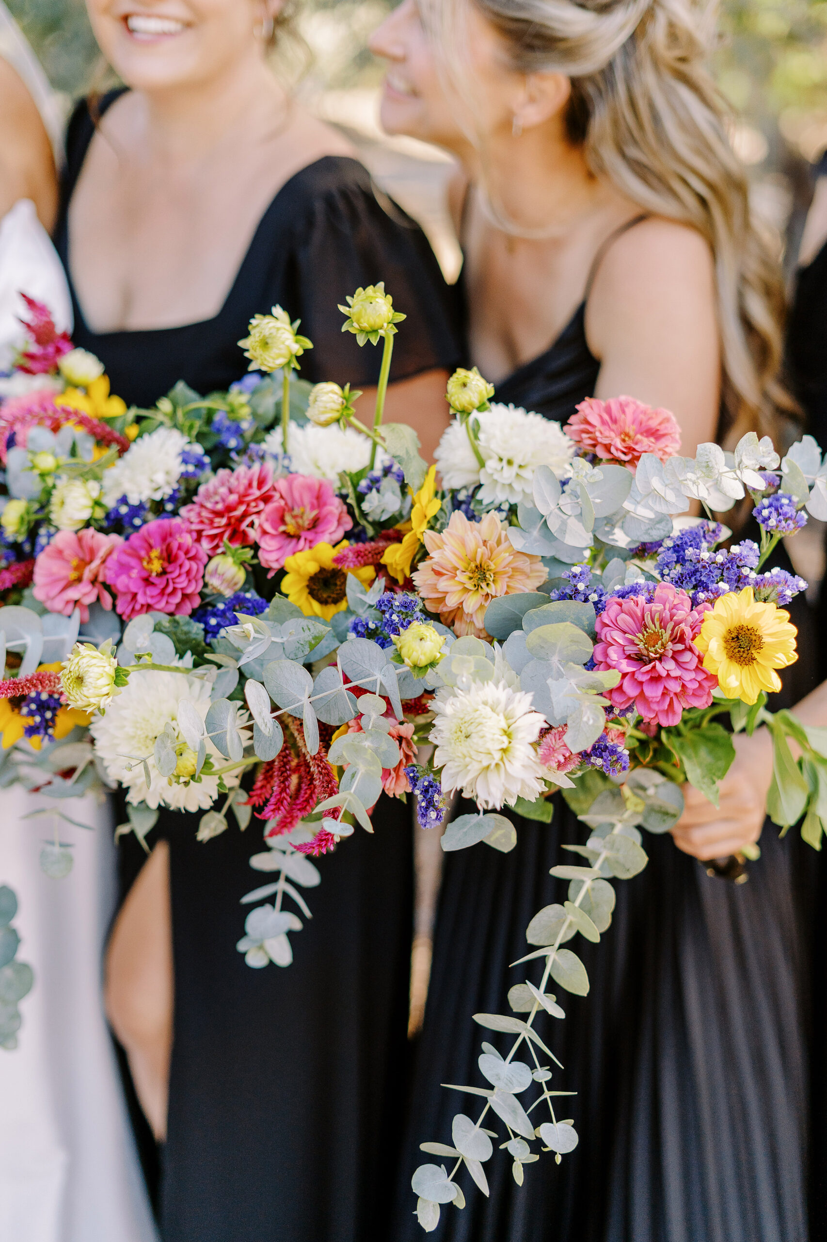 a large 18 person wedding party featuring black dresses with colorful wildflower bouquets for the ladies for a sonoma winery wedding.