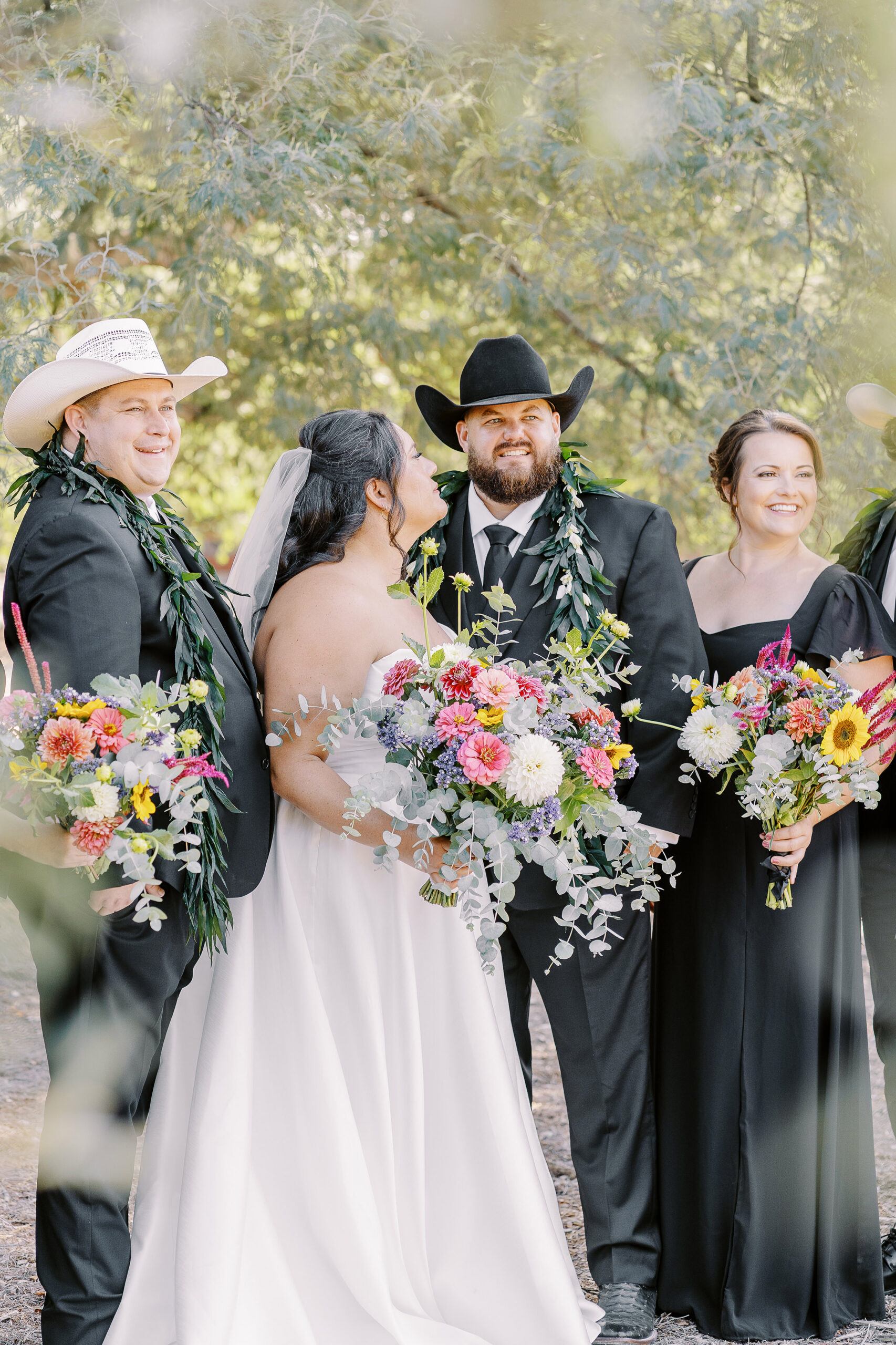 a large 18 persona wedding party featuring black suits and white cowboy hats for the gentlemen and black dresses with colorful wildflower bouquets for the ladies for a sonoma winery wedding.