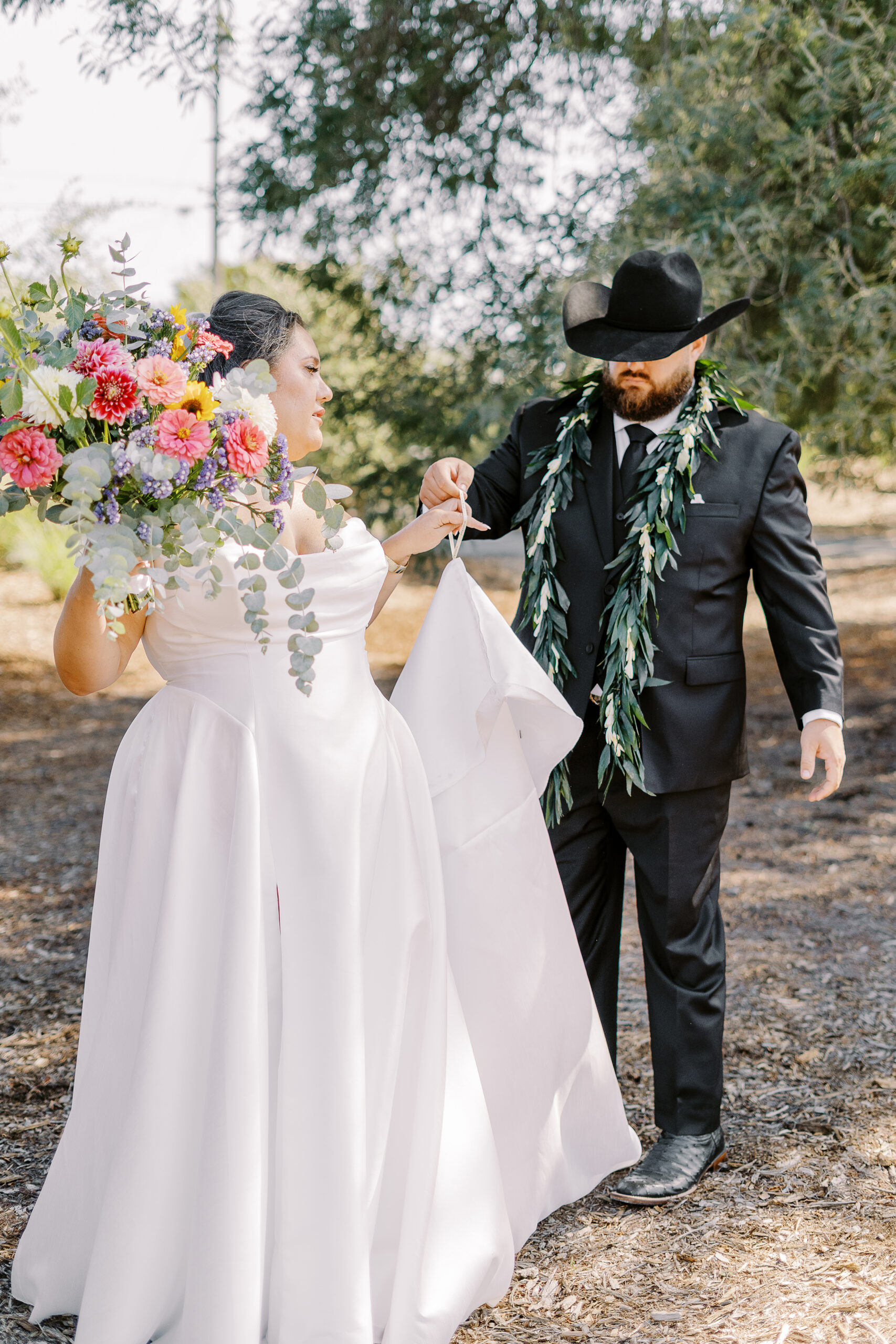 a groom helps his bride with her dress train at their sonoma winery wedding.