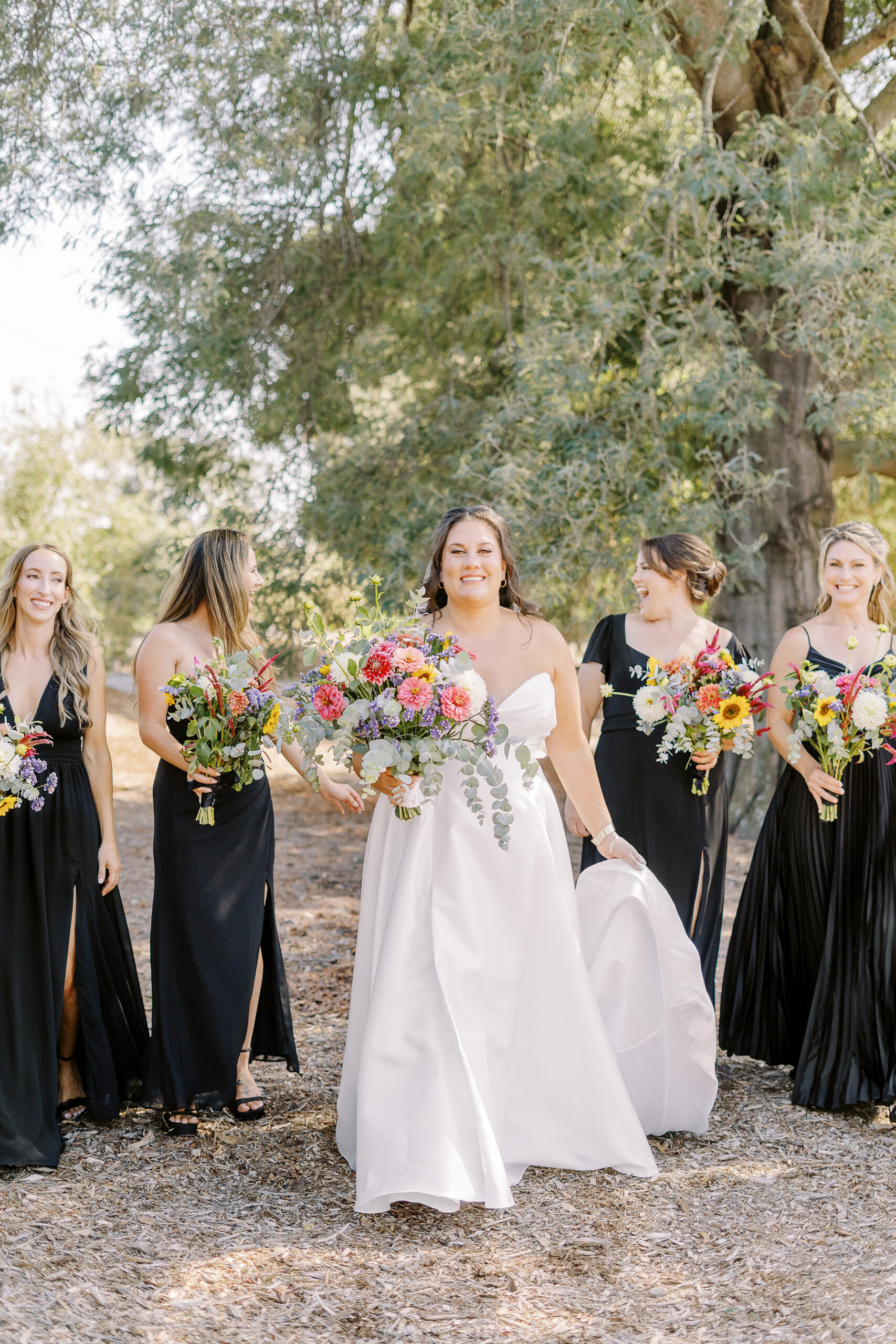 a large 18 person wedding party featuring black dresses with colorful wildflower bouquets for the ladies for a sonoma winery wedding.