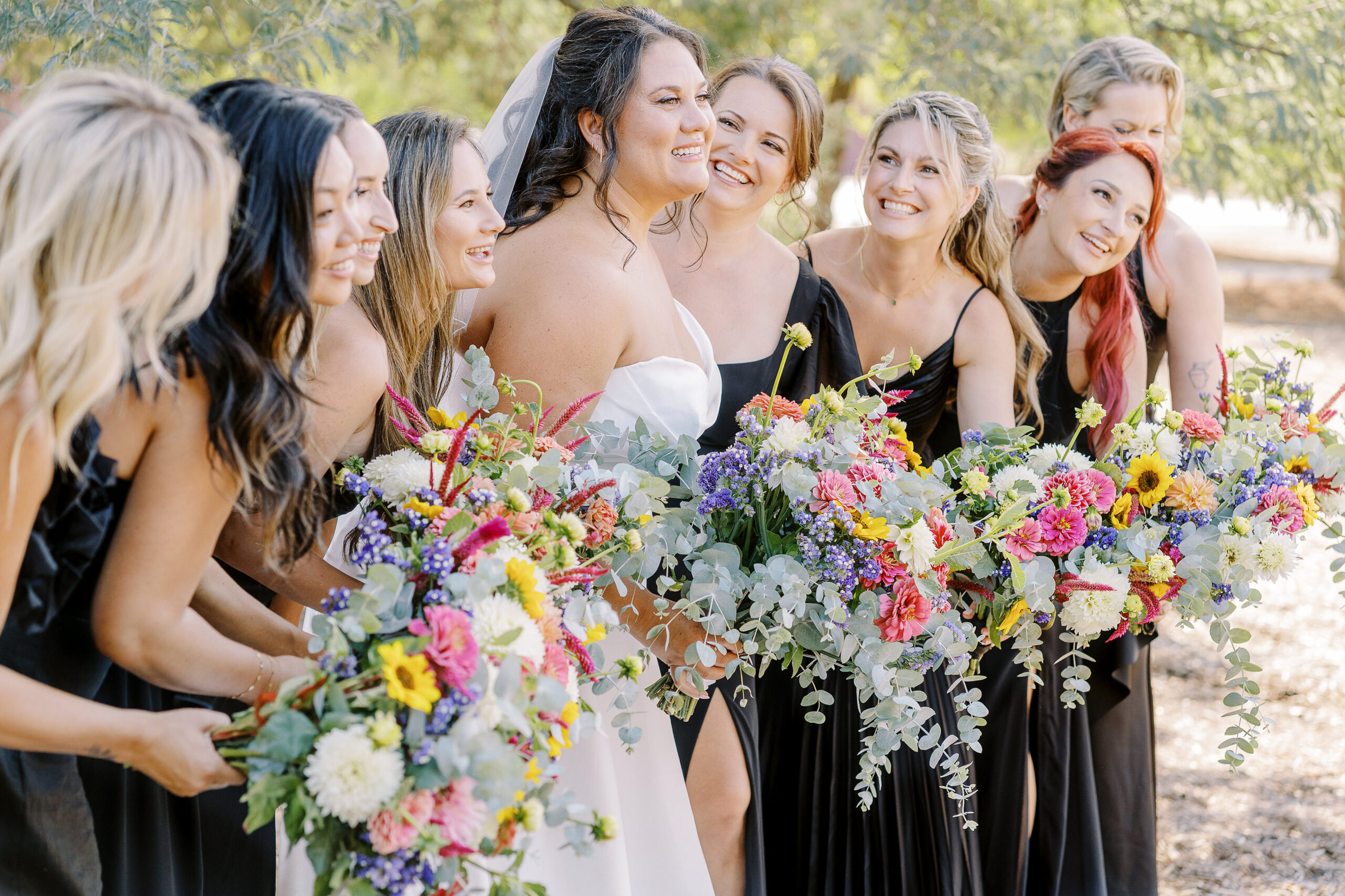a large 18 person wedding party featuring black dresses with colorful wildflower bouquets for the ladies for a sonoma winery wedding.