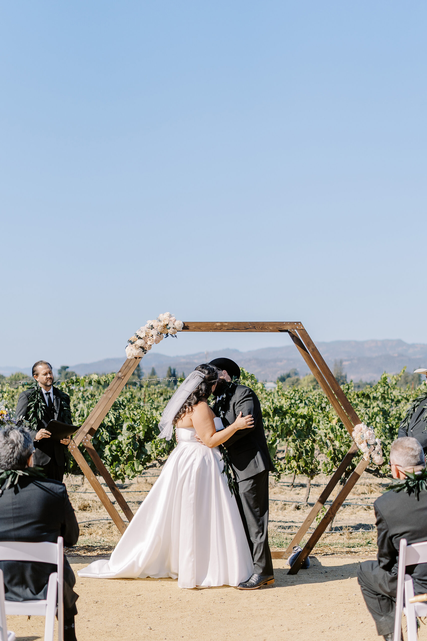 a bride and groom share their first kiss during their sonoma winery wedding ceremony